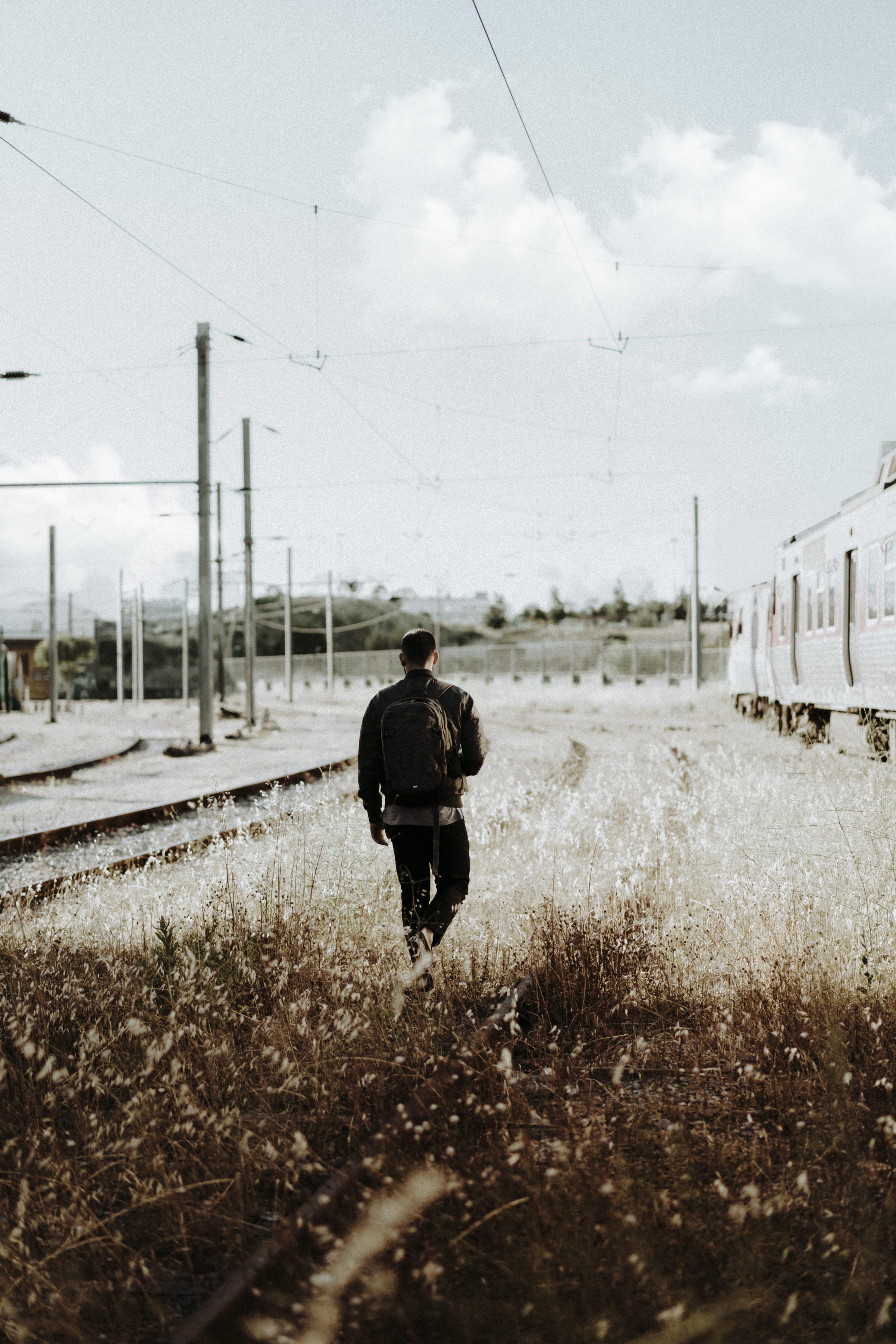 electricity, cloud - sky, train, men, adventure, plant, man, person, near, travel, cable, rail transportation, railroad track, backpack, outdoor, walk, Phone HD Wallpaper