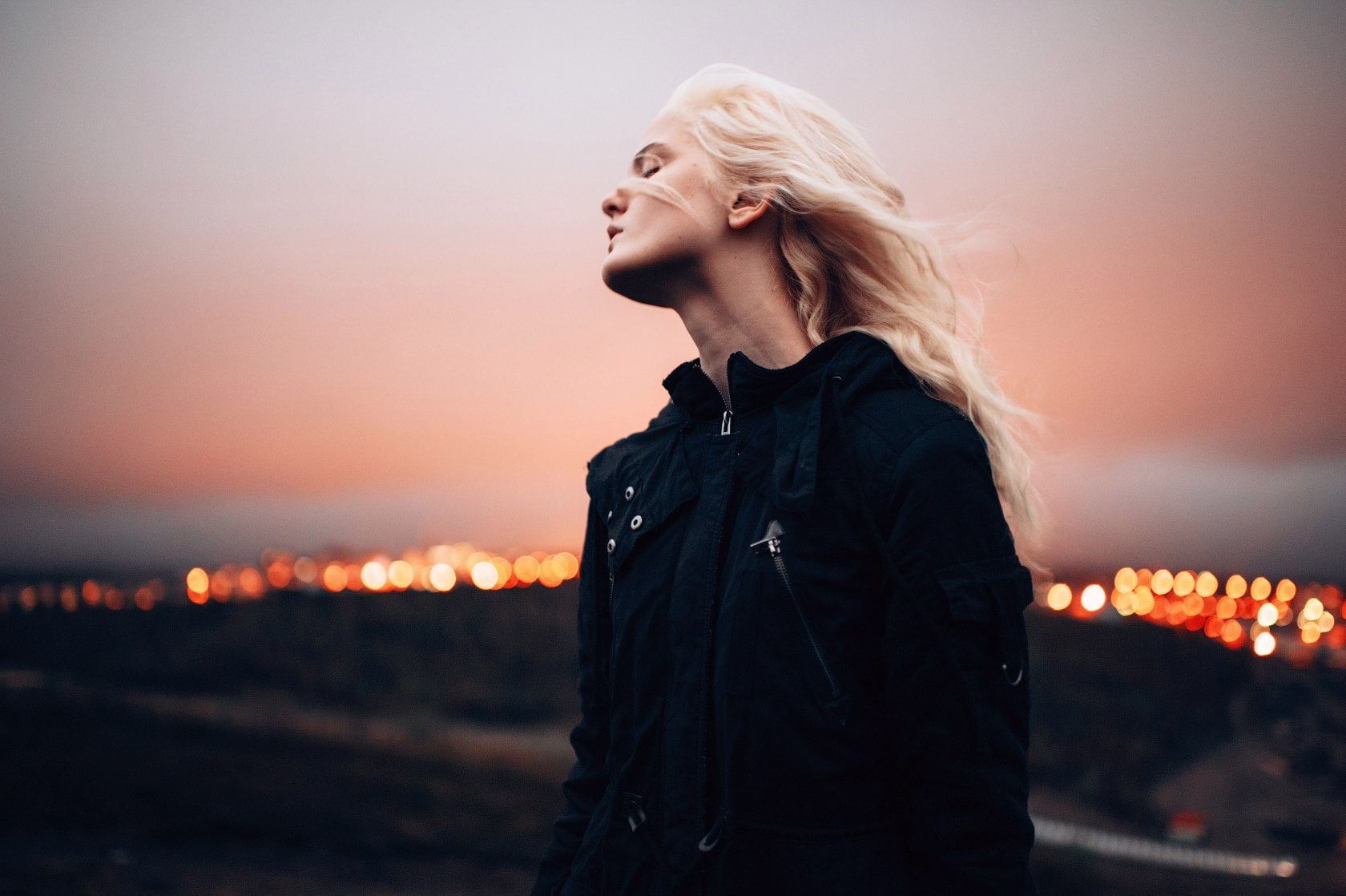 720P, blonde, closed eyes, women, women outdoors, Marat Safin, model, depth of field, city lights, photography, black jackets, windy, black clothing, HD Wallpaper