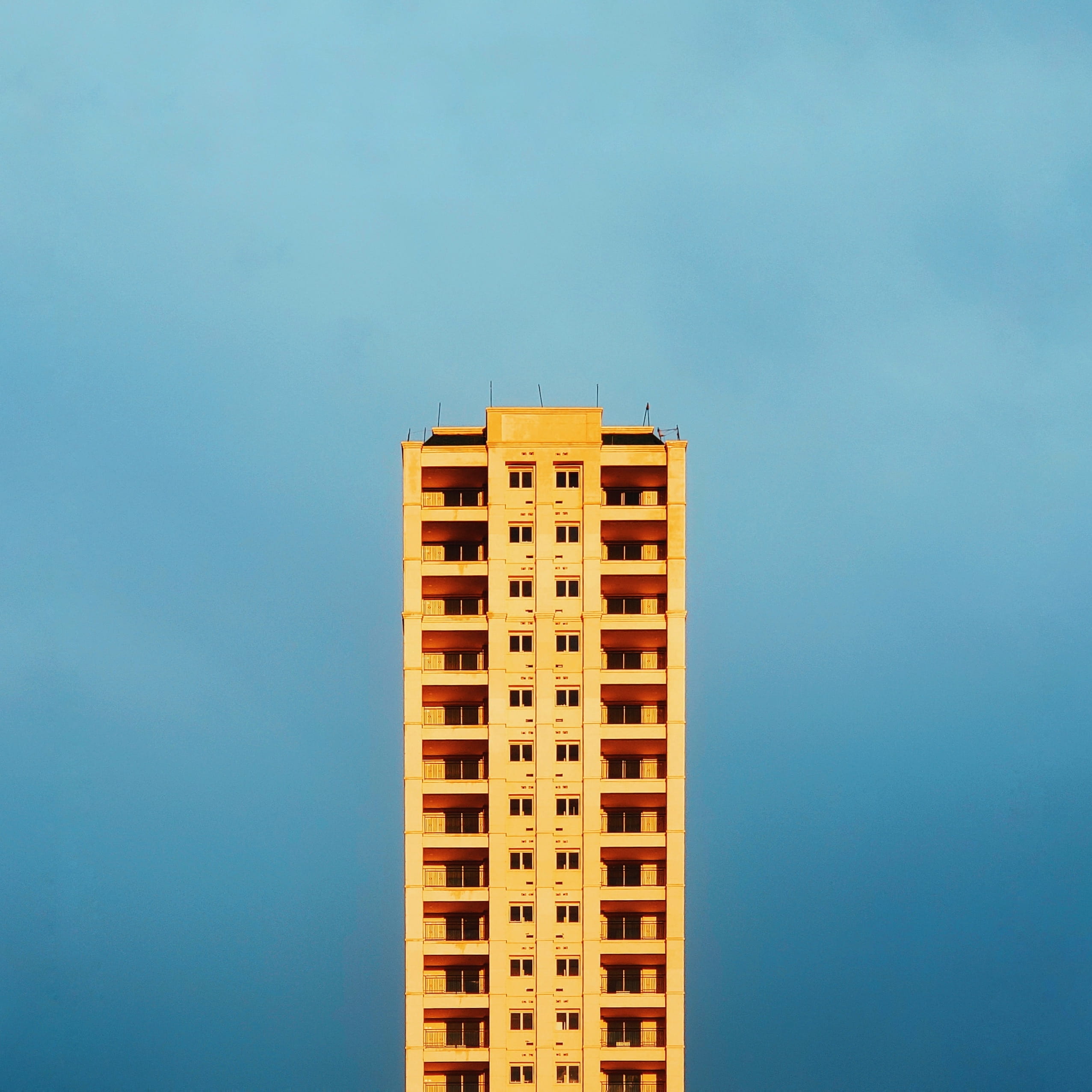 high, building exterior, built structure, architecture, sky, building, copy space, urban, city, outdoors, day, wall - building feature, beige, yellow, clear sky, Phone HD Wallpaper