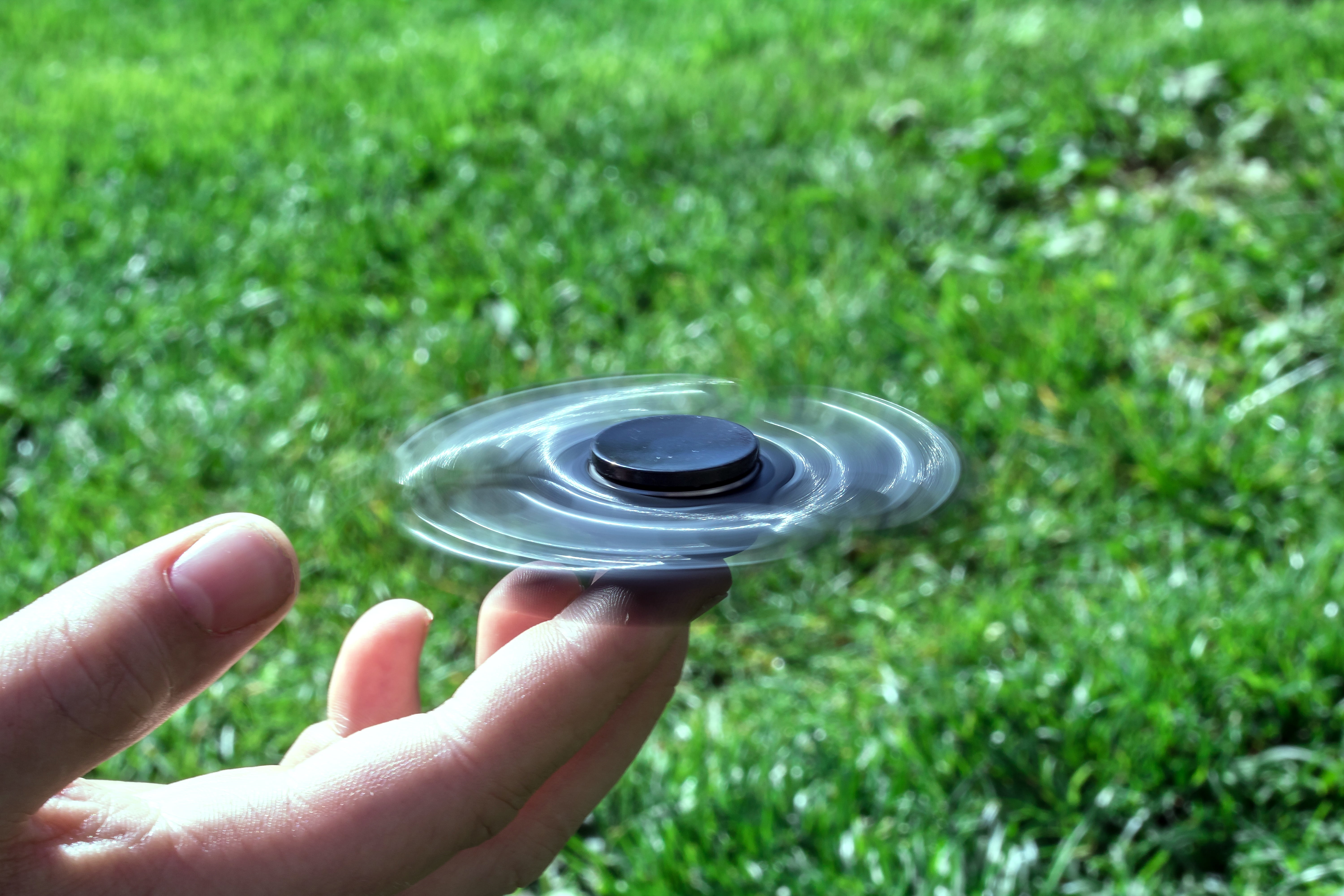 in rotation, 5K, fidget spinner, holding, human body part, field, ball bearings, person, spinner, hand, day, human hand, finger, green color, unrecognizable person, HD Wallpaper