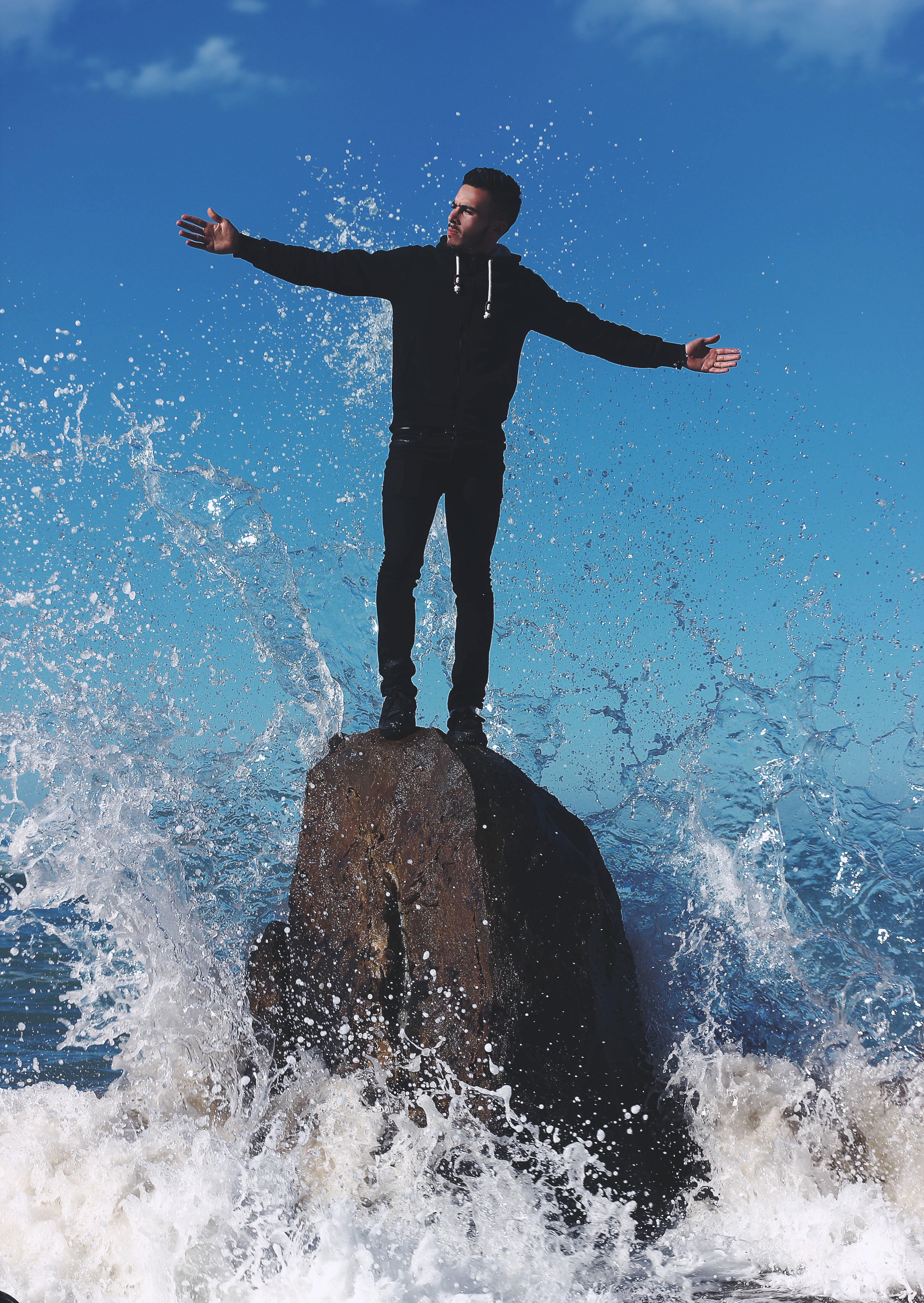 standing, beach, people, water, sea, man, hoodie, leisure activity, splashing, men, young adult, limb, real people, rock, wave, arms outstretched, one person, Phone HD Wallpaper