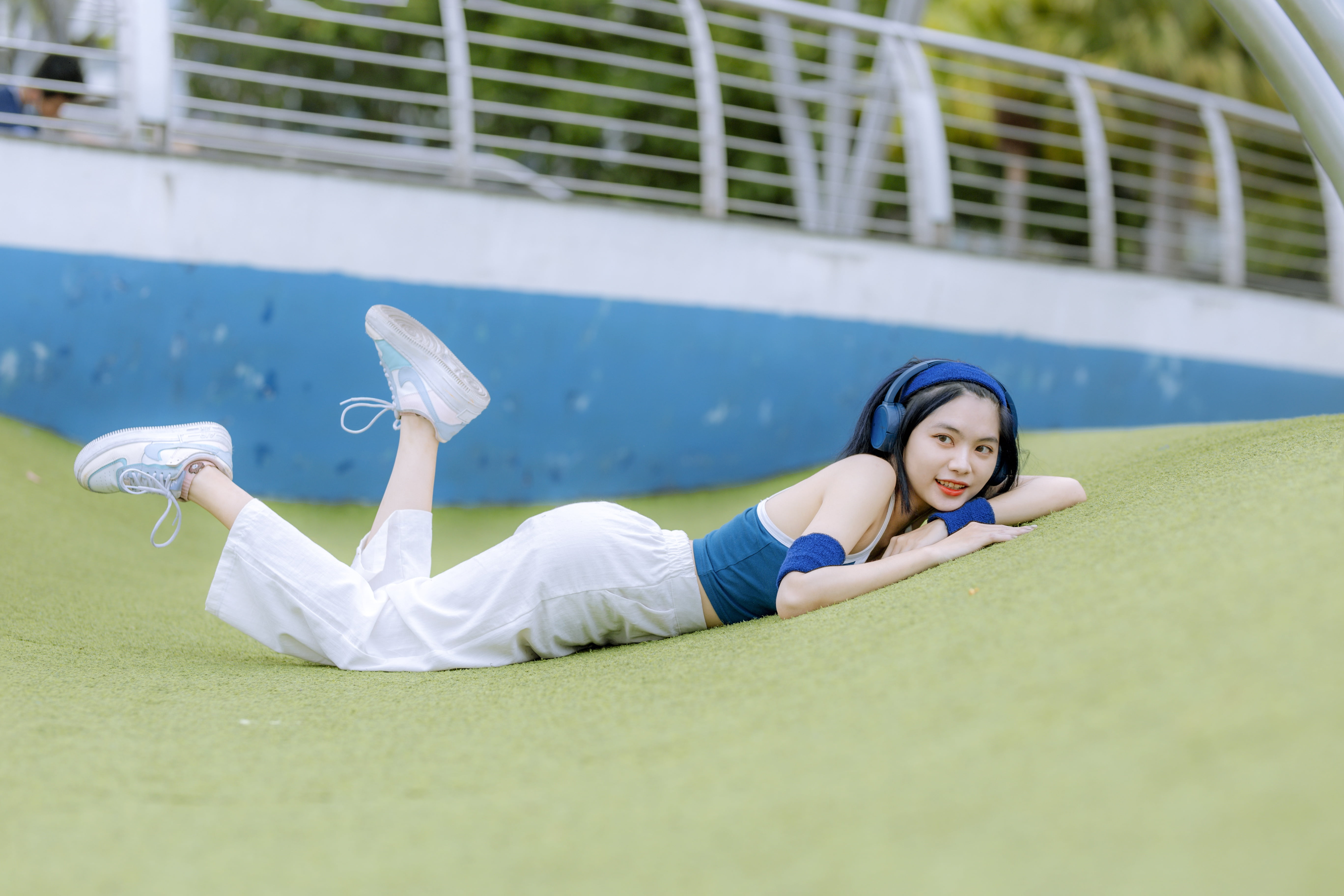 grass, women, lying down, hair band, wristband, Asian, dark hair, 5K, blue tops, depth of field, long hair, pants, sneakers, looking away, headphones, HD Wallpaper