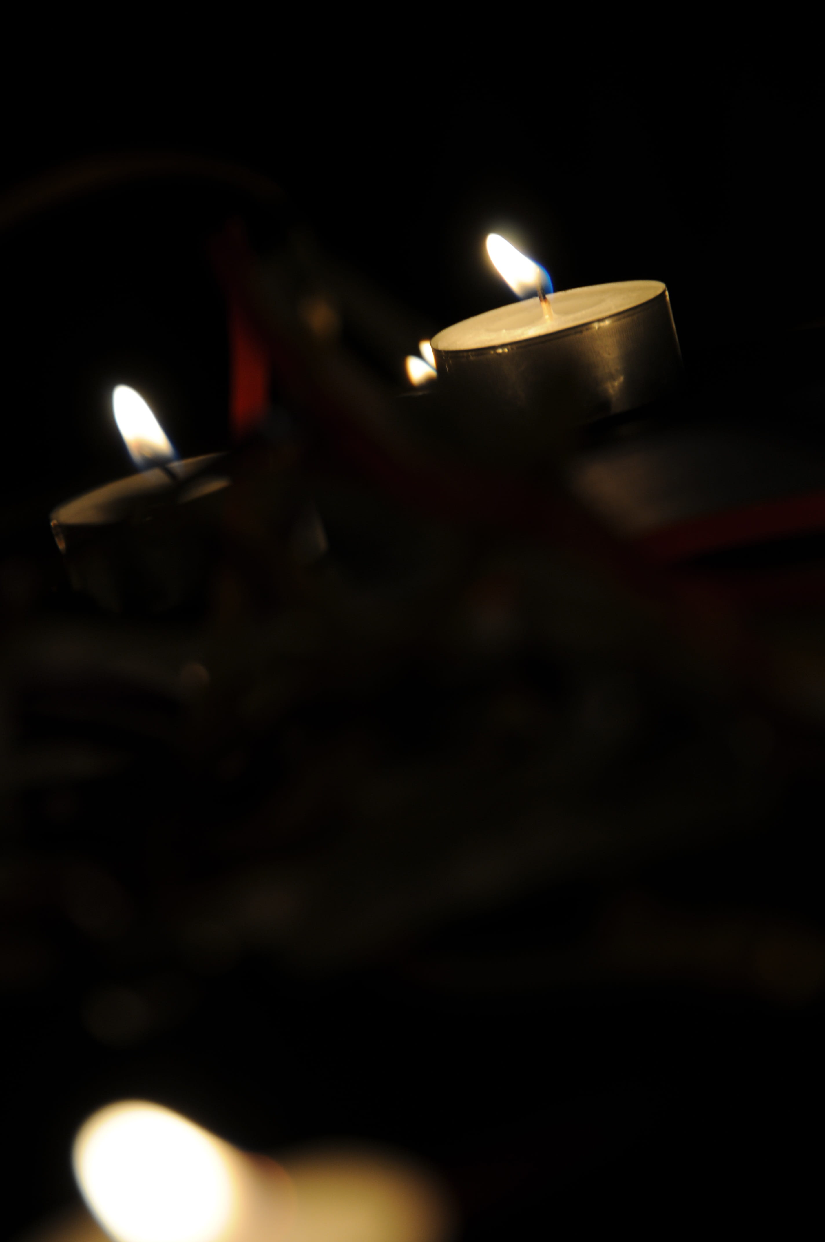 heat - temperature, close-up, Tealight, Candlelight, religion, 4K, tea light, fire, oil lamp, darkness, selective focus, luminosity, electric lamp, no people, Phone HD Wallpaper