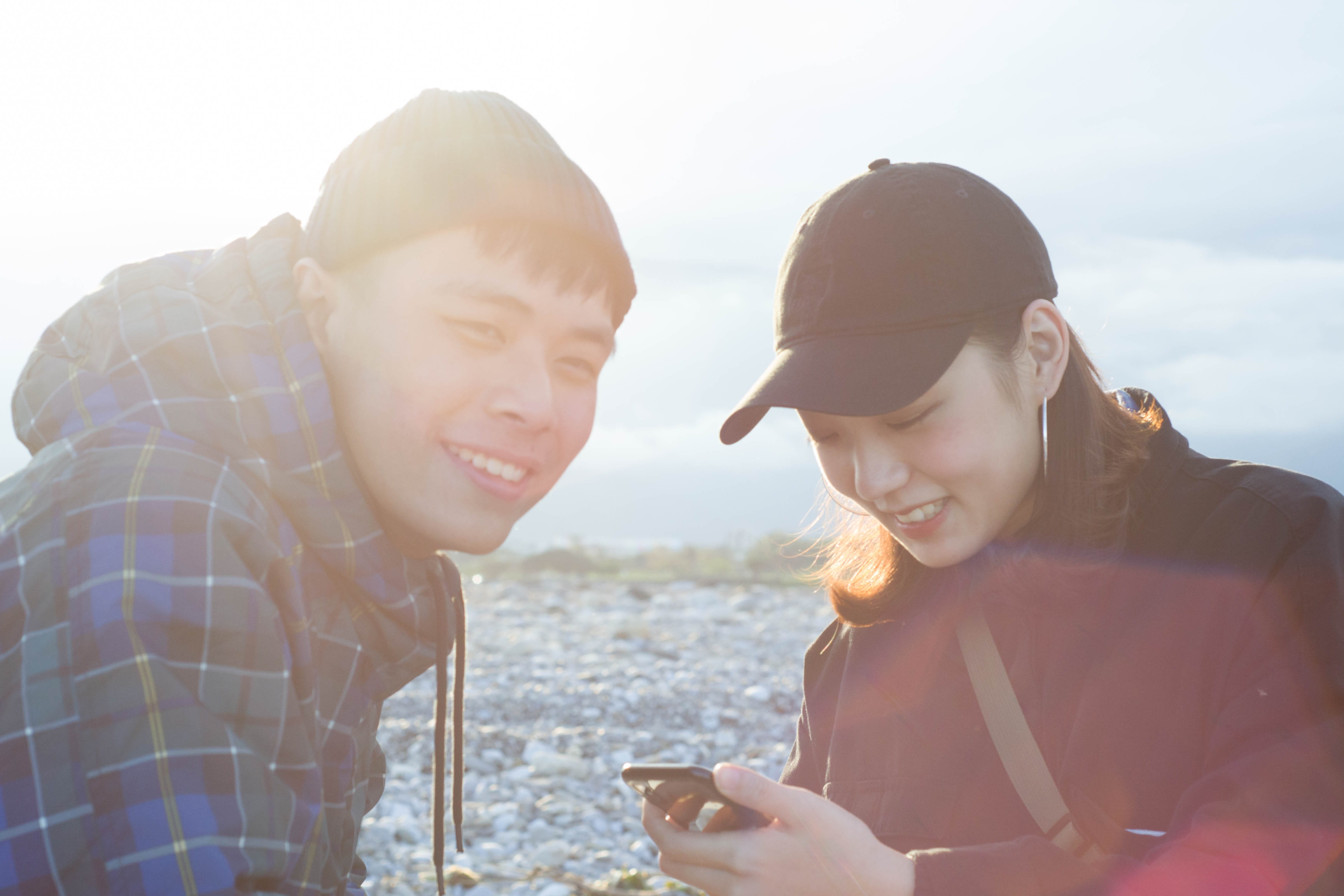 sunlight, photo, sun, young adult, togetherness, portrait, lens flare, couple, smiling, women, emotion, apparel, using, beach, baseball cap, 4K, nature, HD Wallpaper