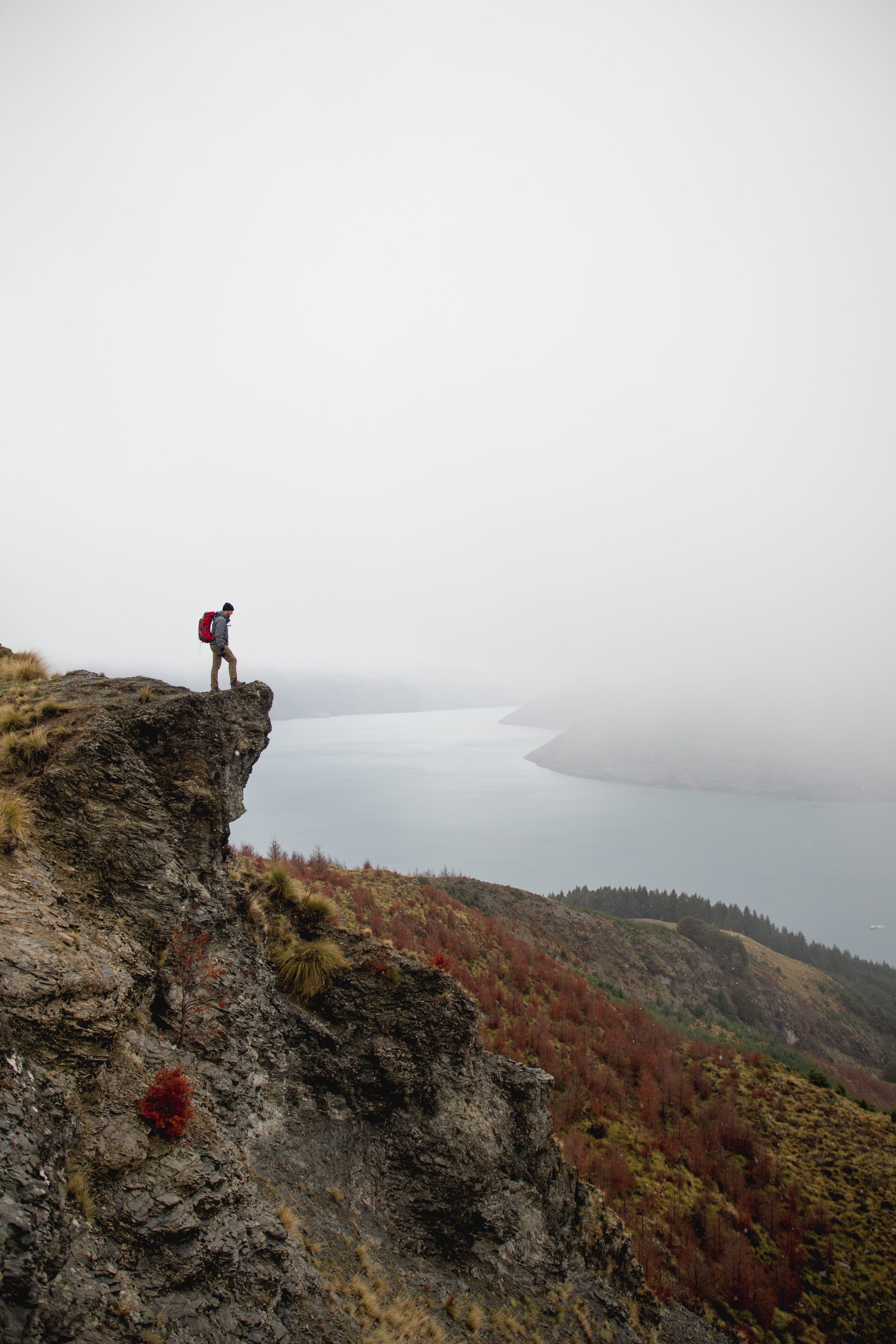 backpack, tranquil scene, sitting on the edge, rock, sky, scenics - nature, fog, plateau, lifestyles, mountain, looking, river, activity, cliff, 5K, rock - object, Phone HD Wallpaper
