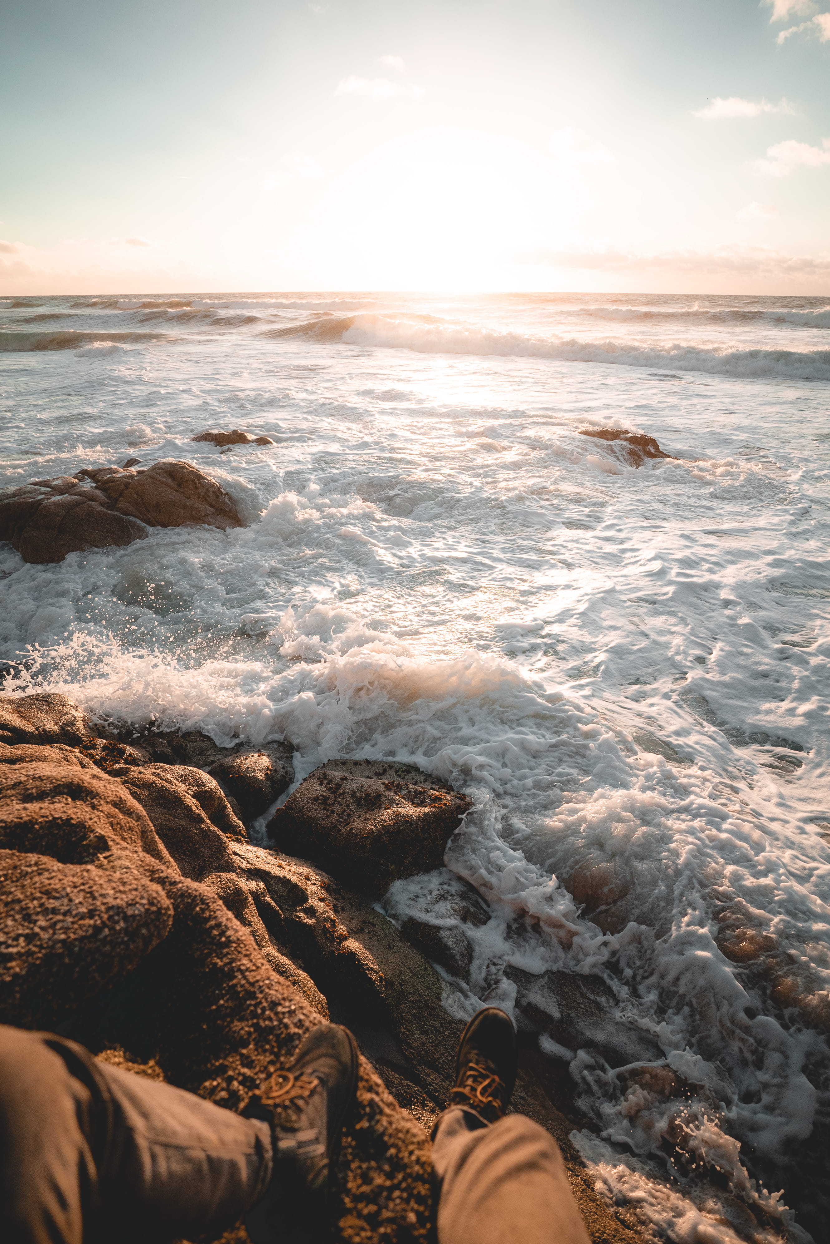 outdoors, beauty in nature, footwear, body part, sea, beach, apparel, rocks, solid, person, clothing, aquatic sport, golden light, sitting, cloud - sky, Phone HD Wallpaper