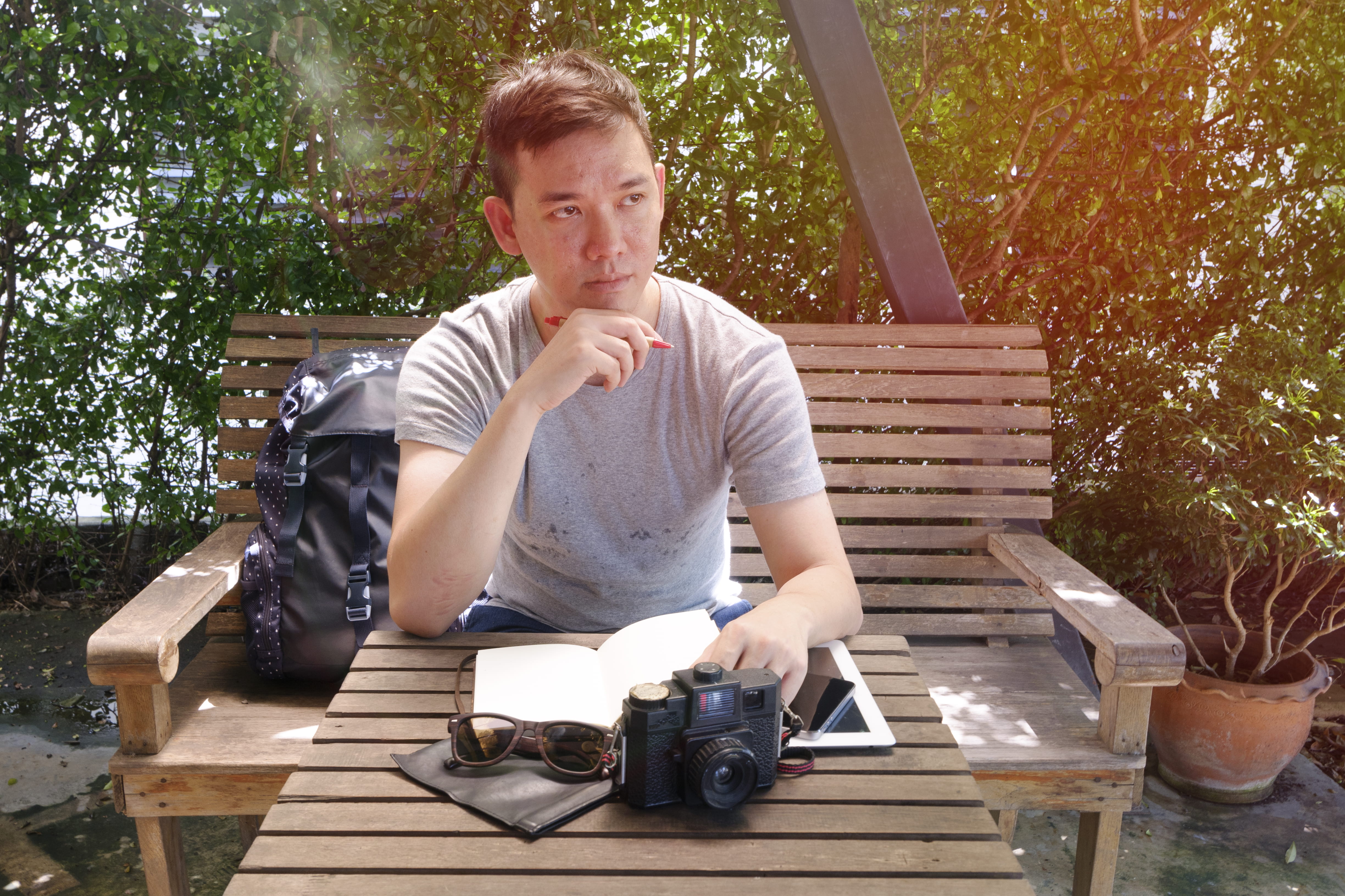 sitting, tourist, bag, young men, portrait, young adult, table, tablet, camera, adult, front view, pot, book, wood, leisure activity, holding, one person, HD Wallpaper