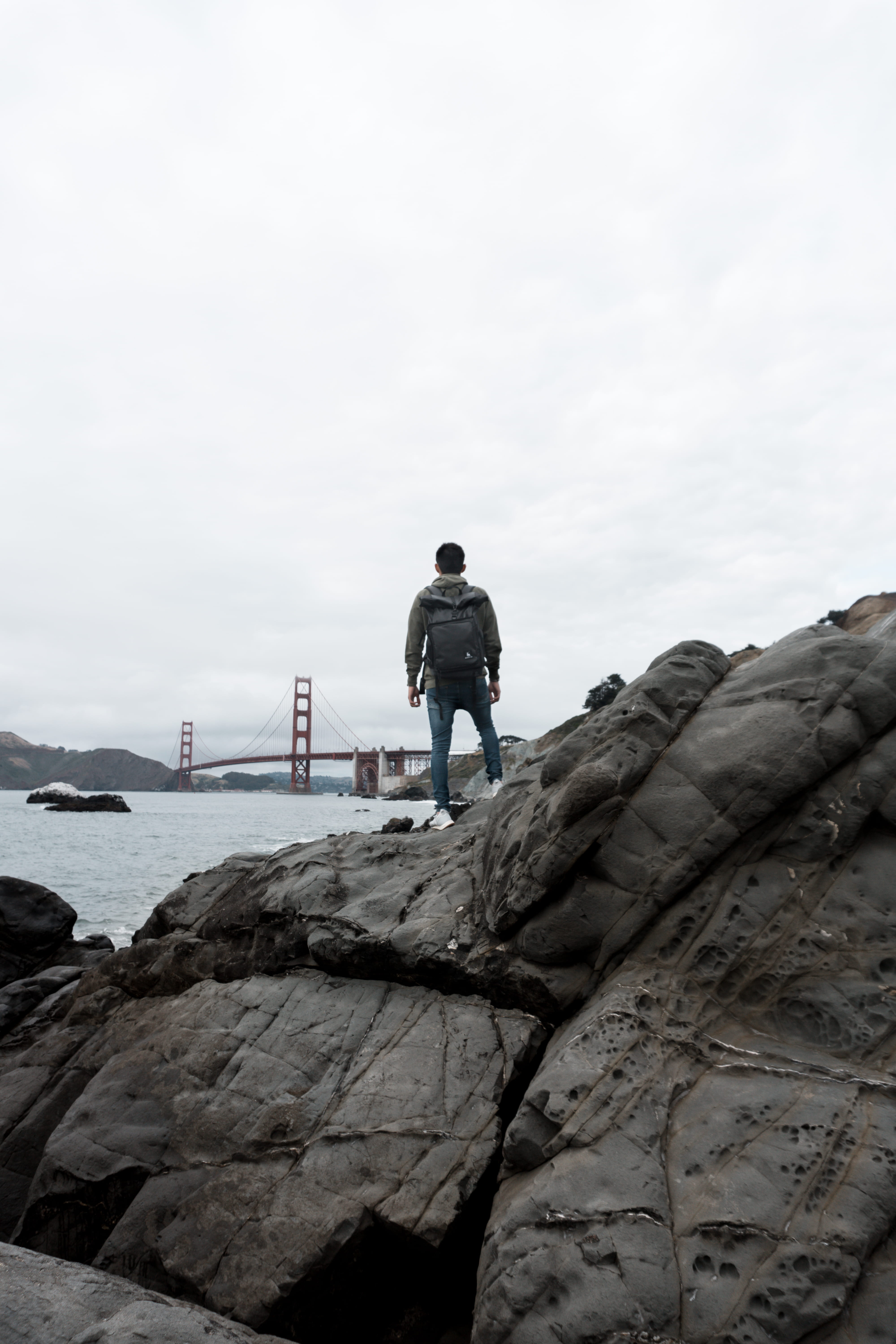 rear view, rocks, backpack, real people, warm clothing, united states, water, lifestyles, outdoors, portrait, solid, rock - object, baker beach, sky, leisure activity, Phone HD Wallpaper