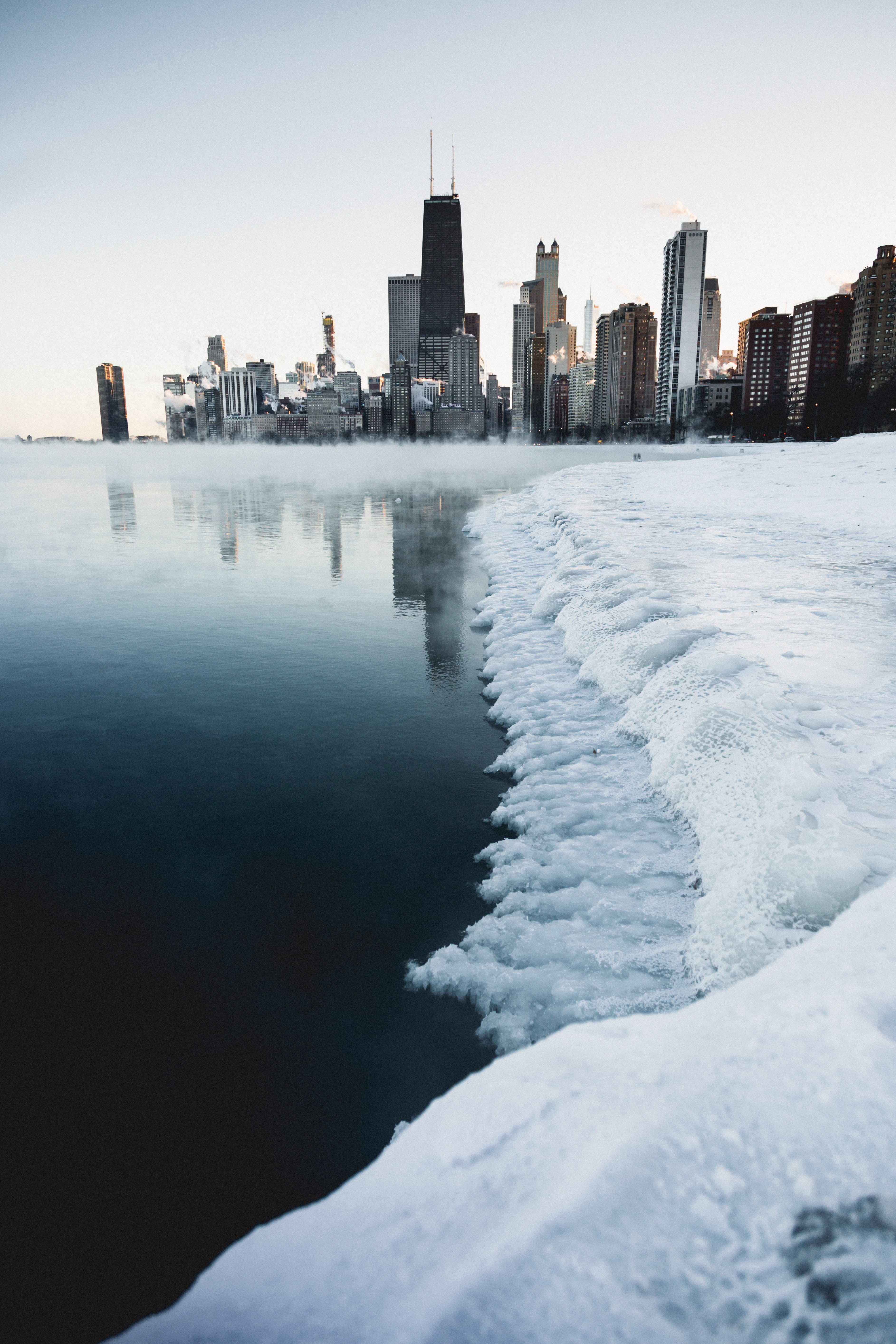 clear sky, cold temperature, sky, sea, reflection, snowy, skyscraper, skyline, city, buildings, cold, winter, modern, season, building exterior, urban skyline, Phone HD Wallpaper