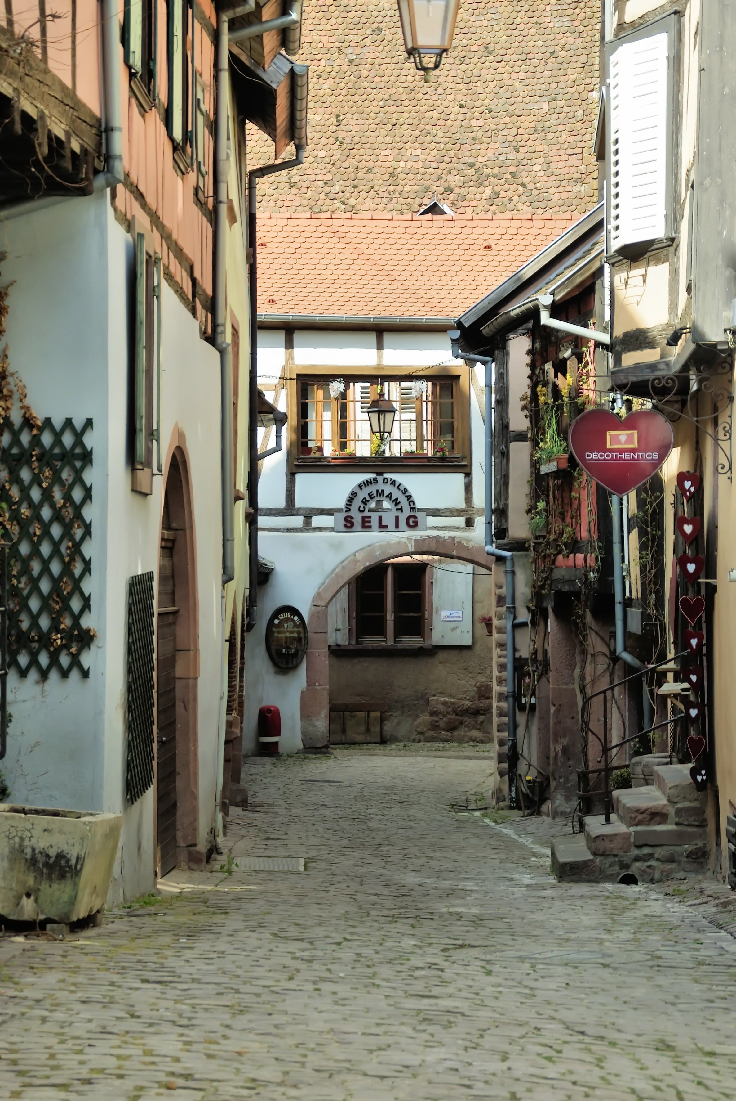building Exterior, europe, direction, picturesque, building, street, transportation, travel, riquewihr, day, narrow, old houses, entrance, city, electric lamp, Phone HD Wallpaper
