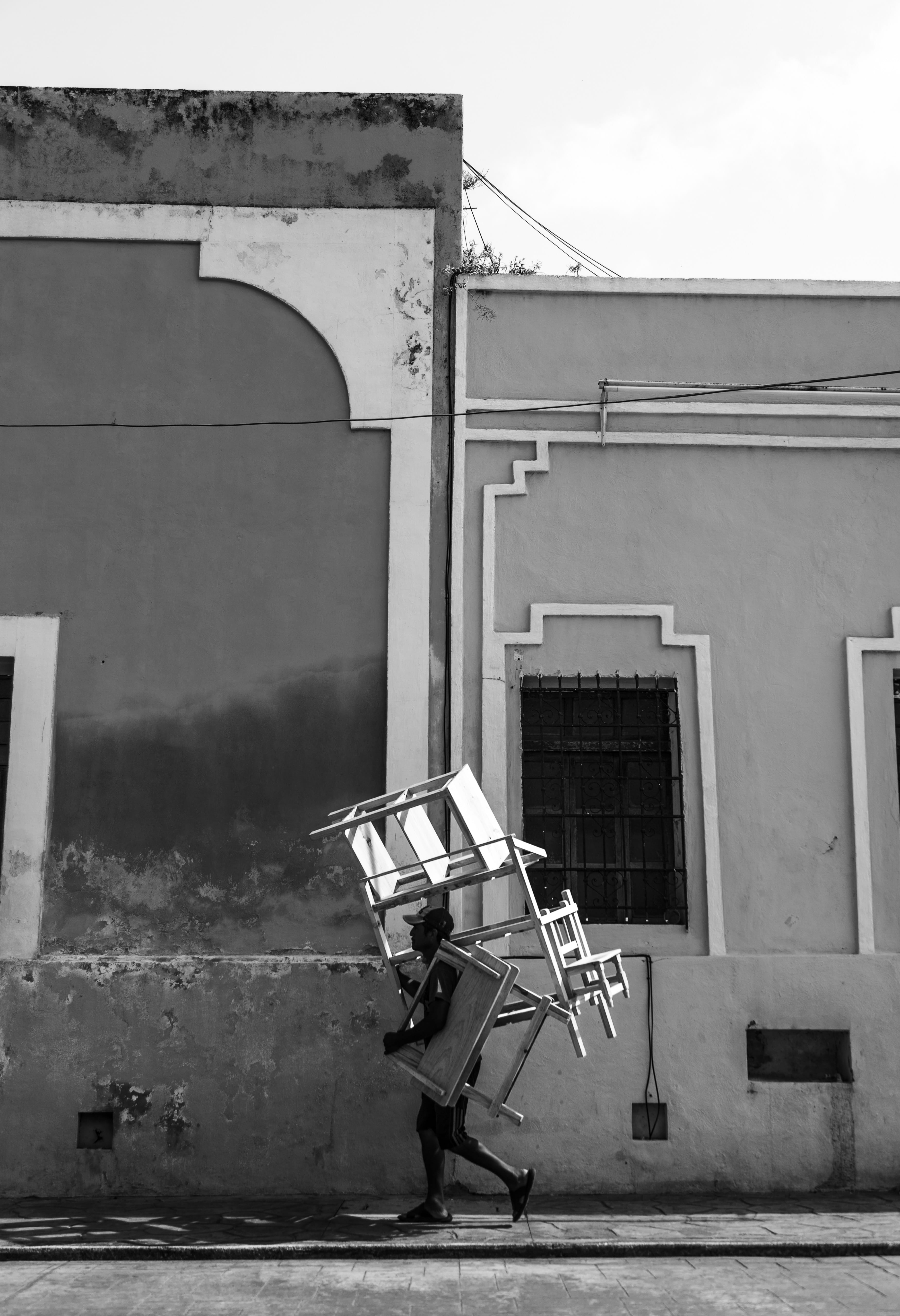 carrying, 5K, grayscale, sunlight, photography, man, footpath, nature, street, old, black and white, walking, building, building exterior, concrete, bicycle, Phone HD Wallpaper