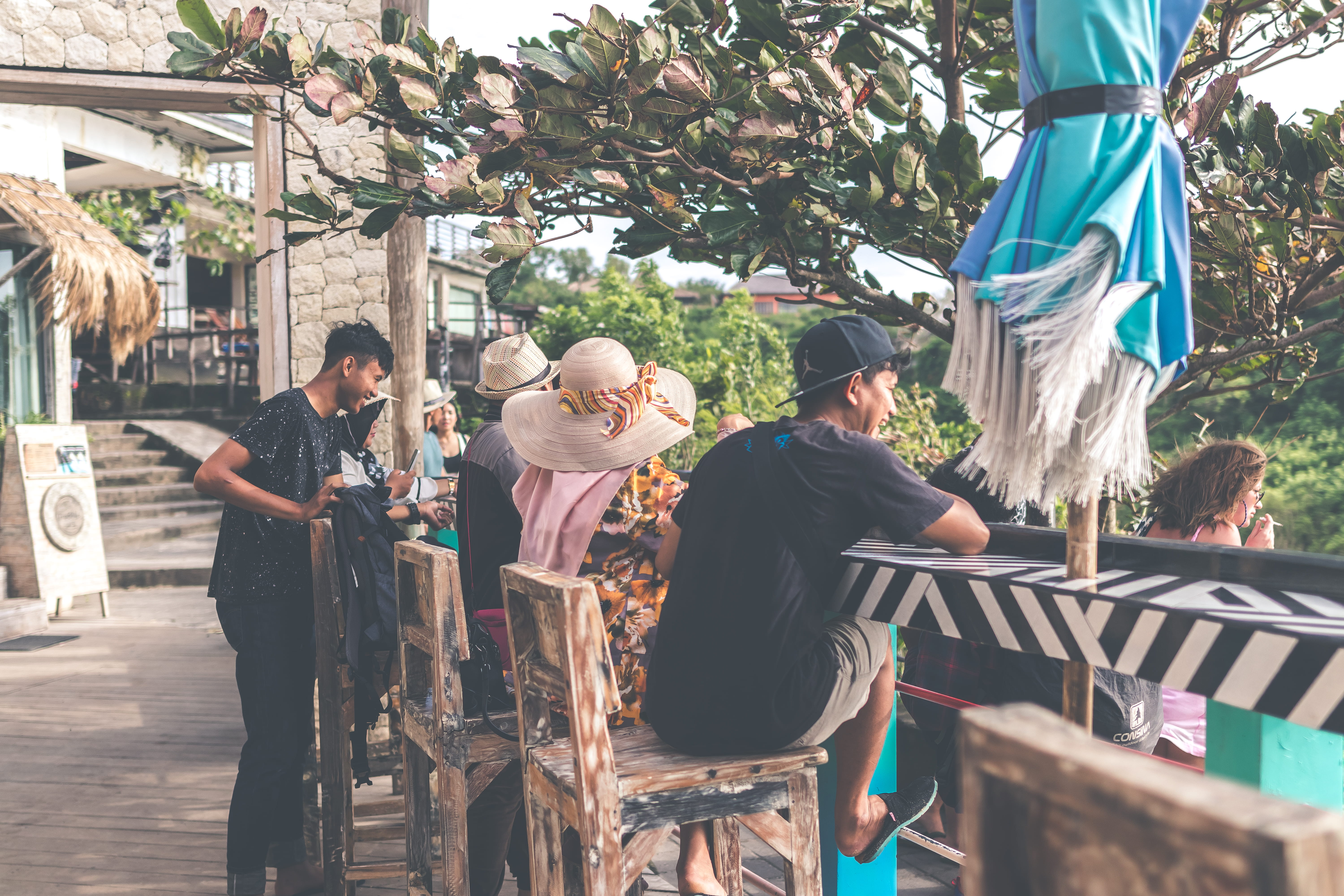 landmark, restaurant, promenade, women, outdoors, man, sitting, men, black, town, shorts, wooden, plant, resort, wear, group, tourism, stool, lifestyles, HD Wallpaper