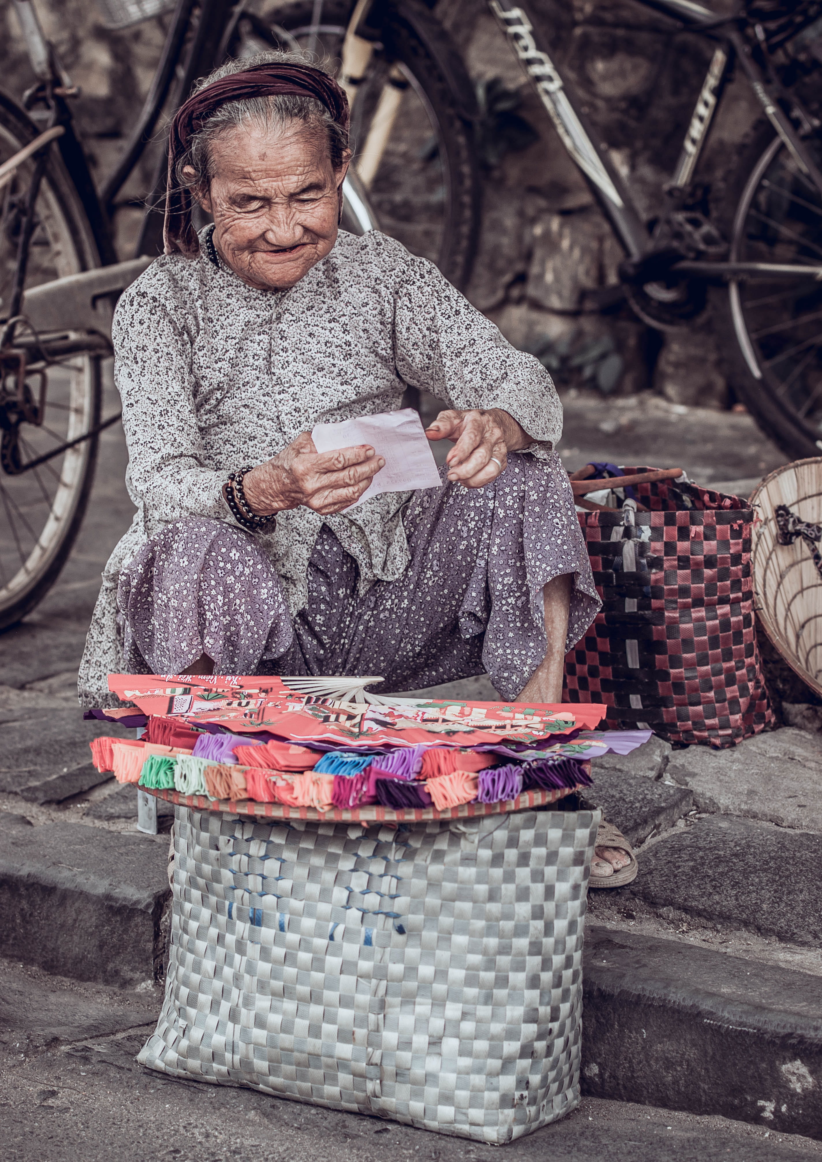 portrait, woman, street, men, concrete, sitting, smile, age, holding, fan, selling, clothing, scarf, near, fans, streetlife, grey, males, read, mature adult, Phone HD Wallpaper