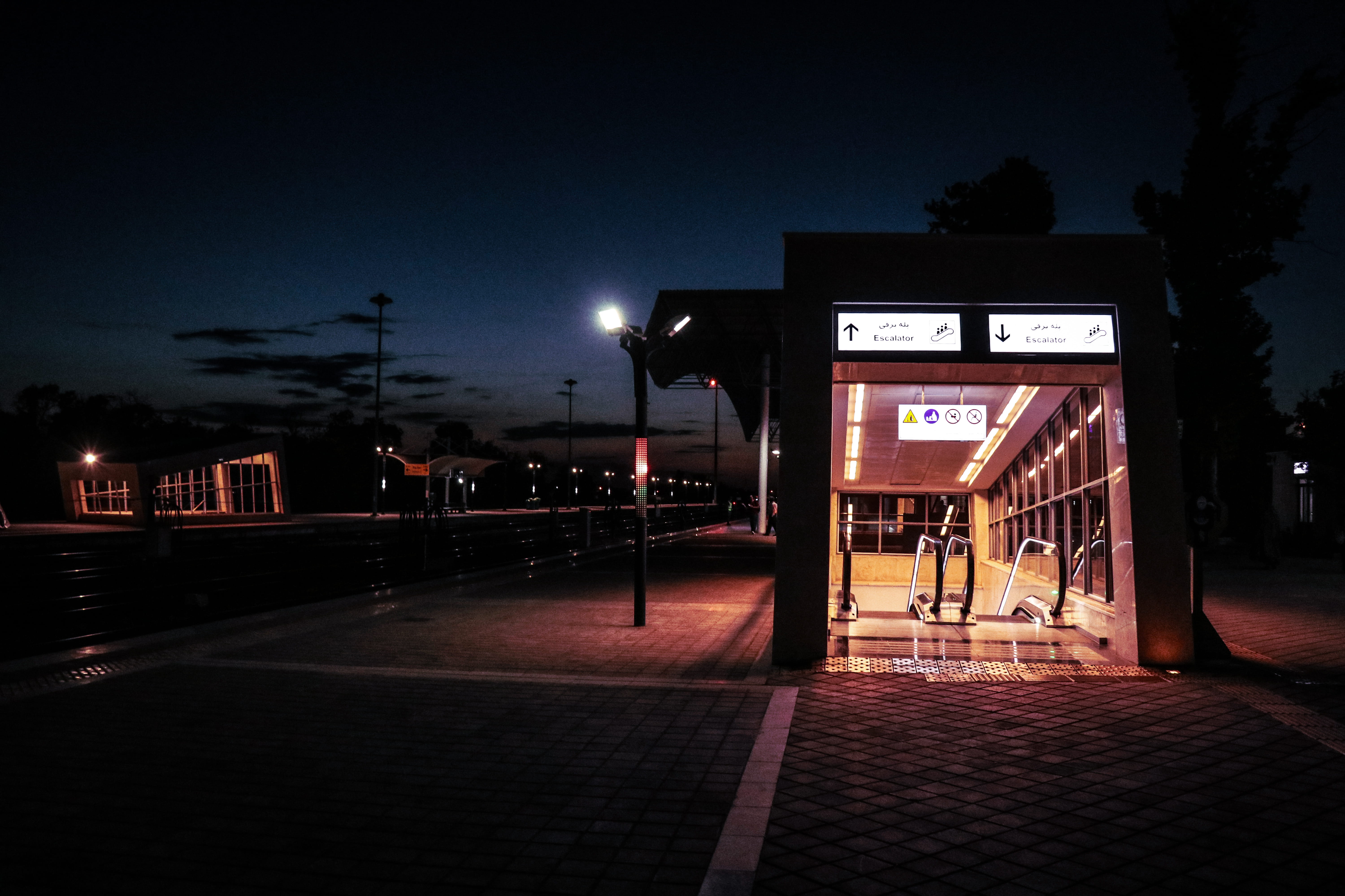 western script, city, train, outdoors, path, vehicle, door, communication, lighting equipment, flooring, tarmac, pedestrian, sky, terminal, dusk, person, HD Wallpaper