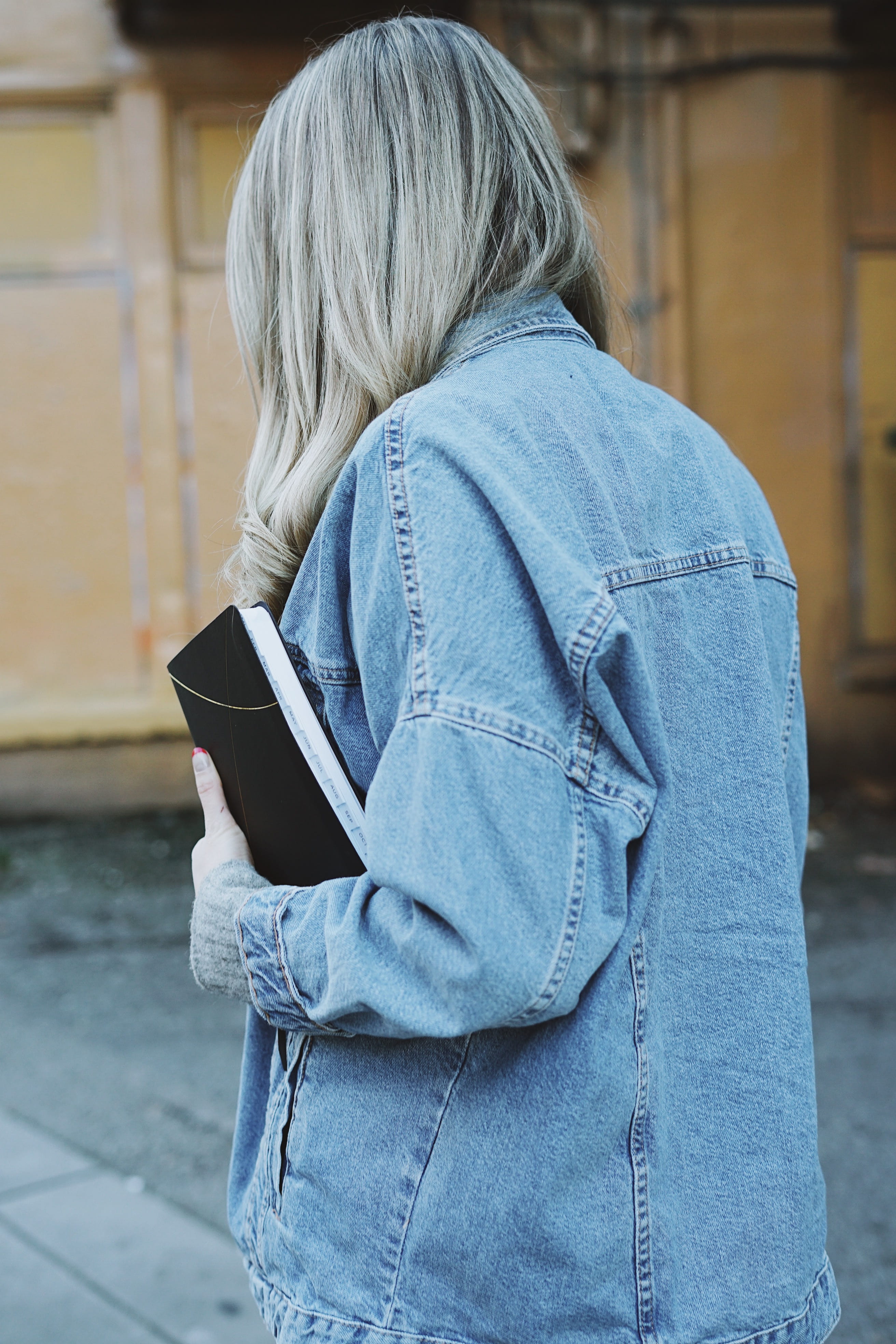 waist up, lifestyles, holding, human, warm clothing, casual clothing, long sleeve, jacket, black, wood, focus on foreground, paper, sweater, jeans, book, Phone HD Wallpaper