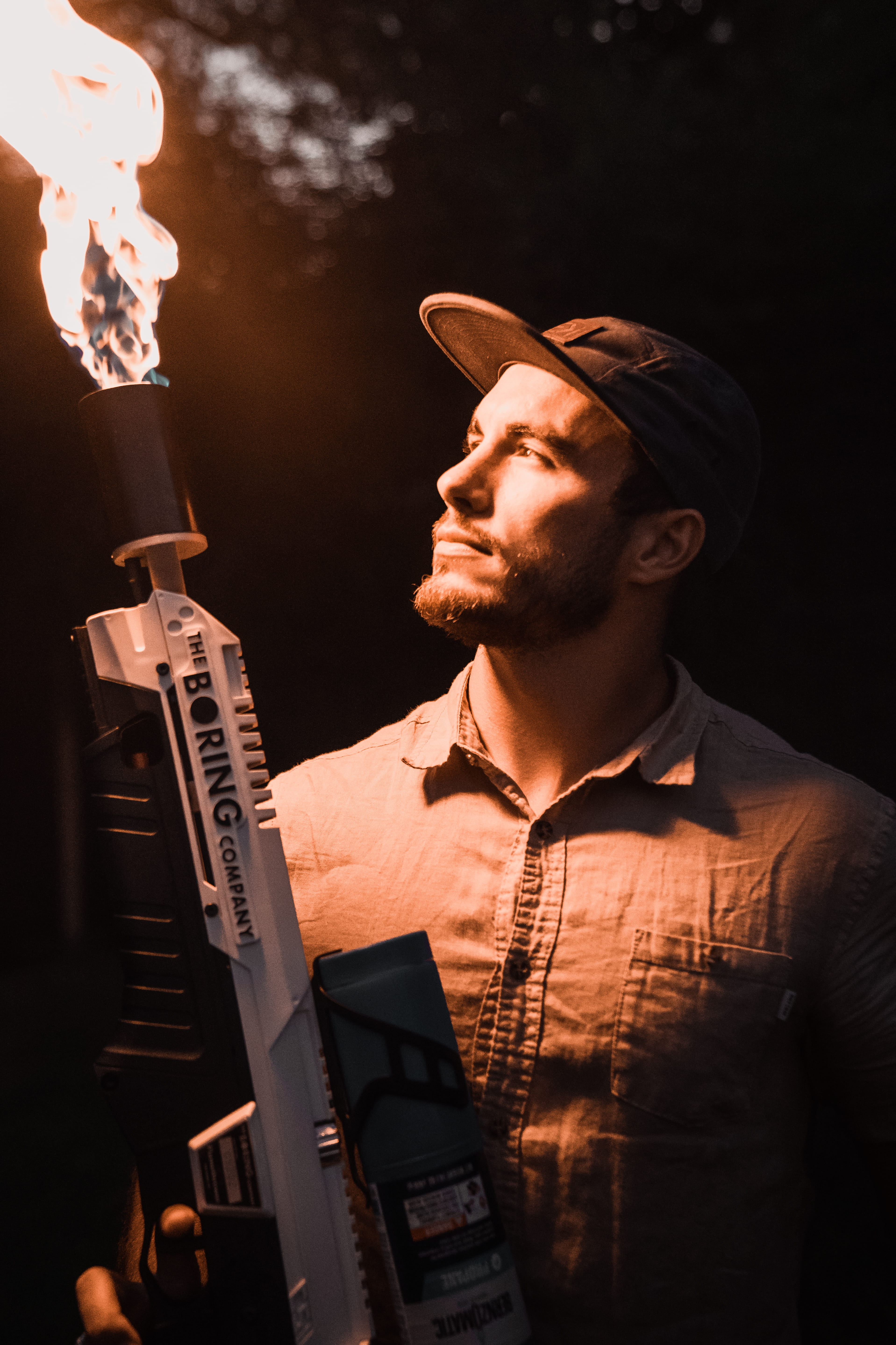 flamethrower, front view, holding, men, looking away, hat, 5K, clothing, facial hair, adult, man, black background, young adult, males, mid adult, real people, Phone HD Wallpaper