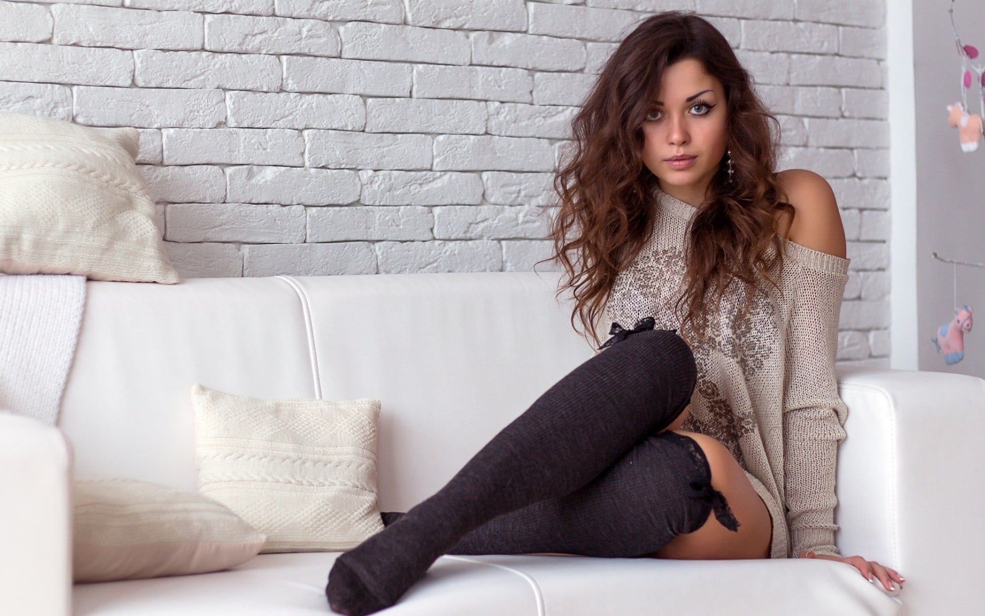 socks, couch, bare shoulders, model, looking at viewer, 1080P, sweater, wavy hair, brunette, knee-highs, women, bricks, long hair, HD Wallpaper