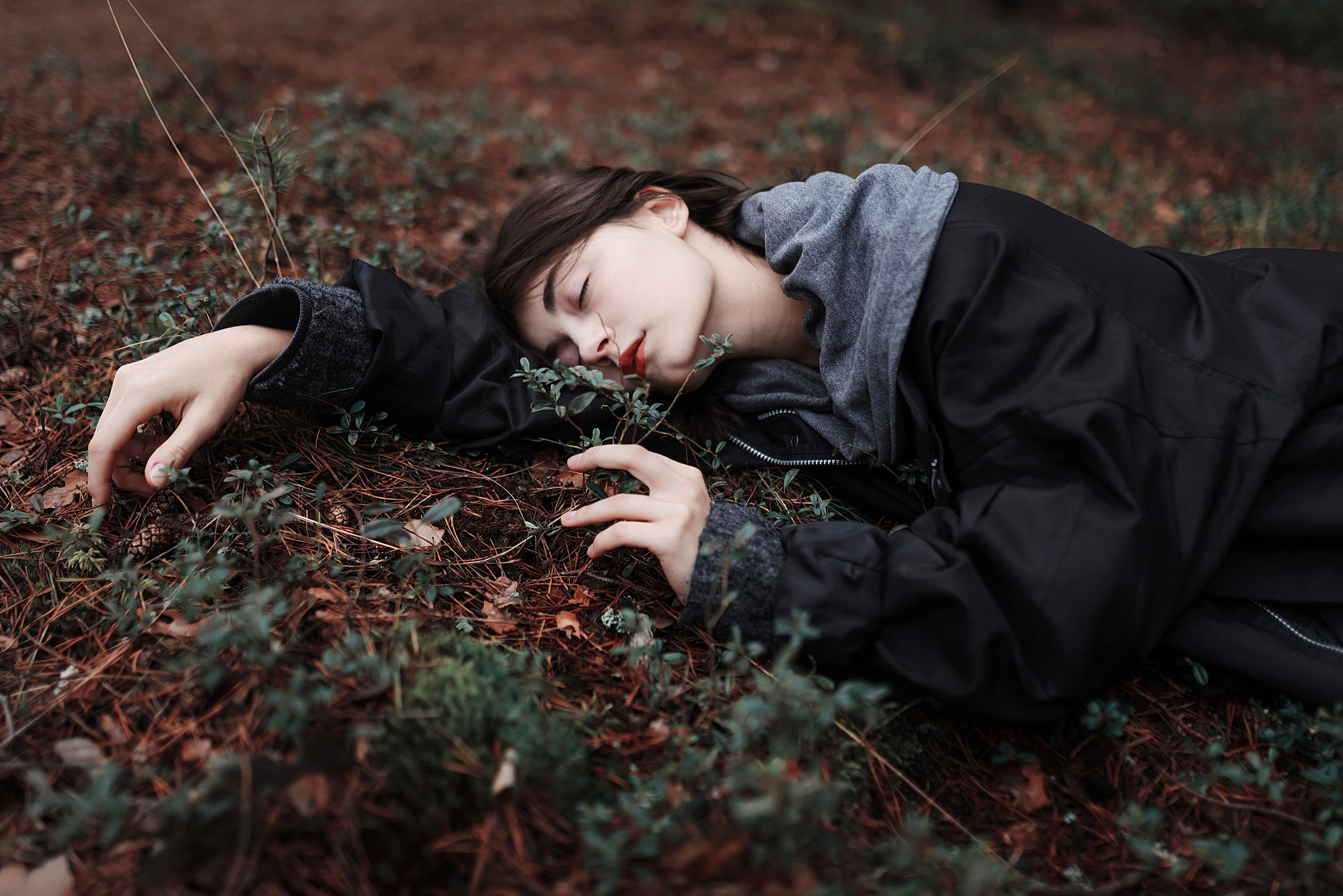 on the floor, outdoors, brunette, pine cones, jacket, plants, forest, women outdoors, bokeh, red lipstick, women, portrait, lying on side, closed eyes, HD Wallpaper