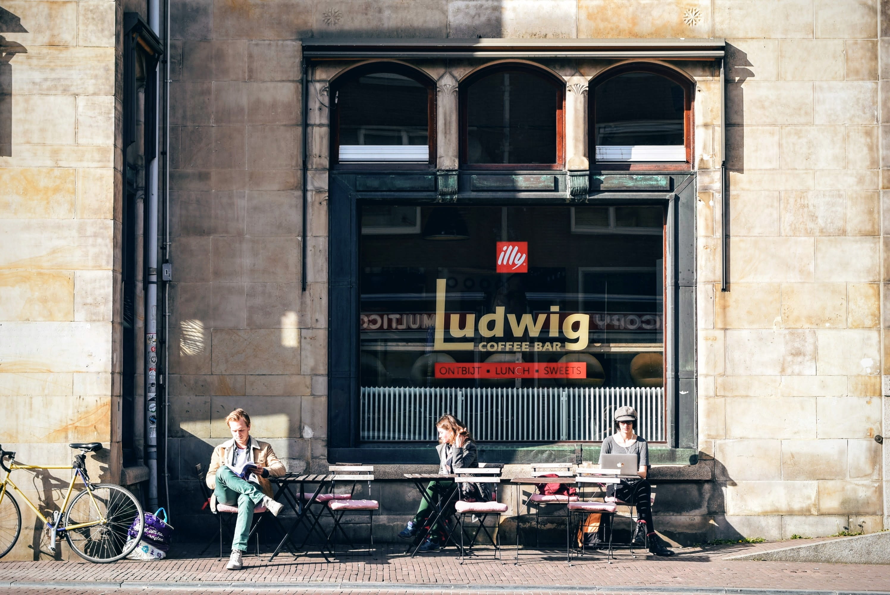 tourism, bicycle, road, sitting, downtown, text, bench, outdoors, men, pavement, street, coffee, built structure, city, city life, real people, 2K, coffee shop, HD Wallpaper