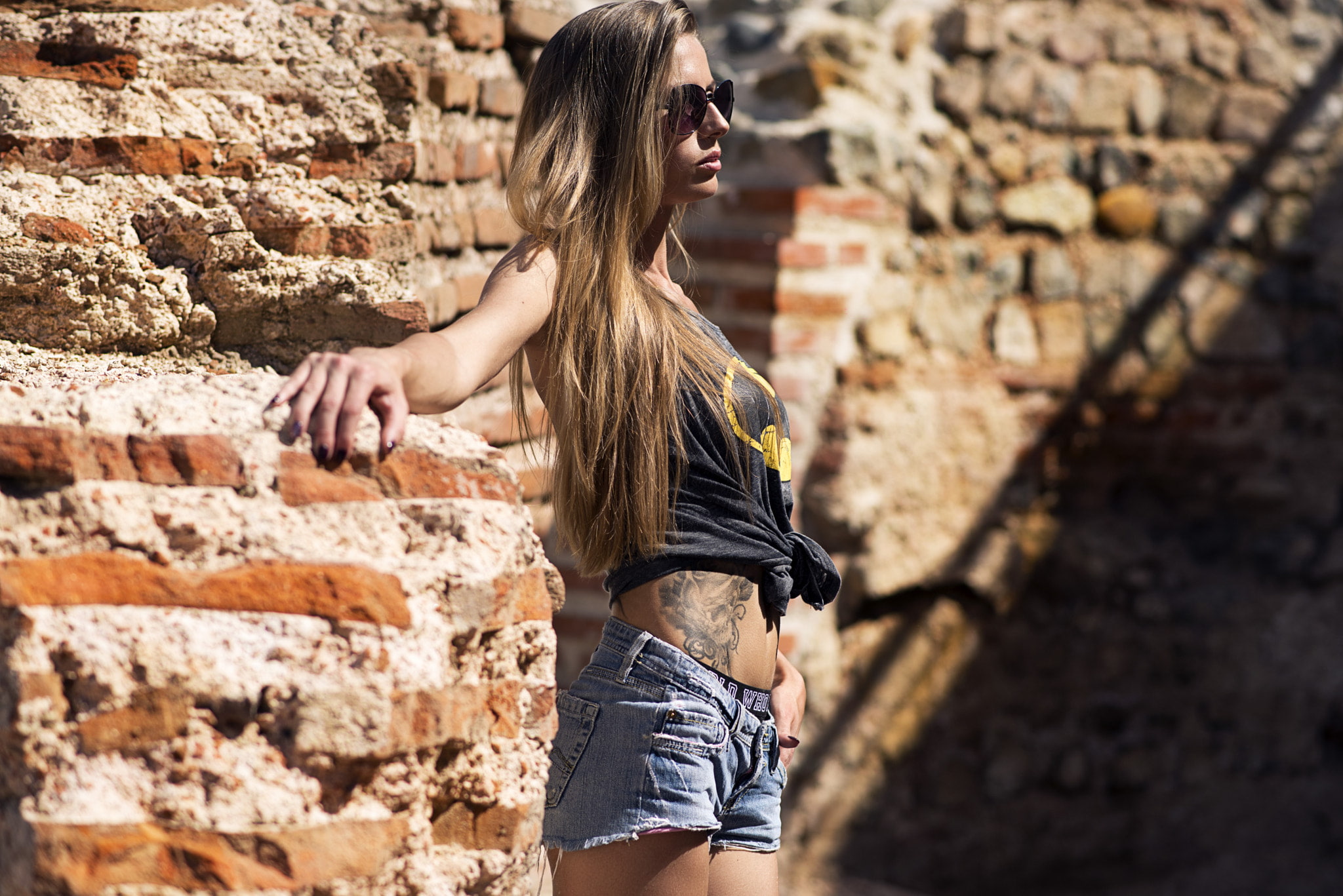 tattoo, skinny, blonde, sunglasses, T-shirt, depth of field, women, belly, long hair, jean shorts, 1080P, bricks, looking away, HD Wallpaper