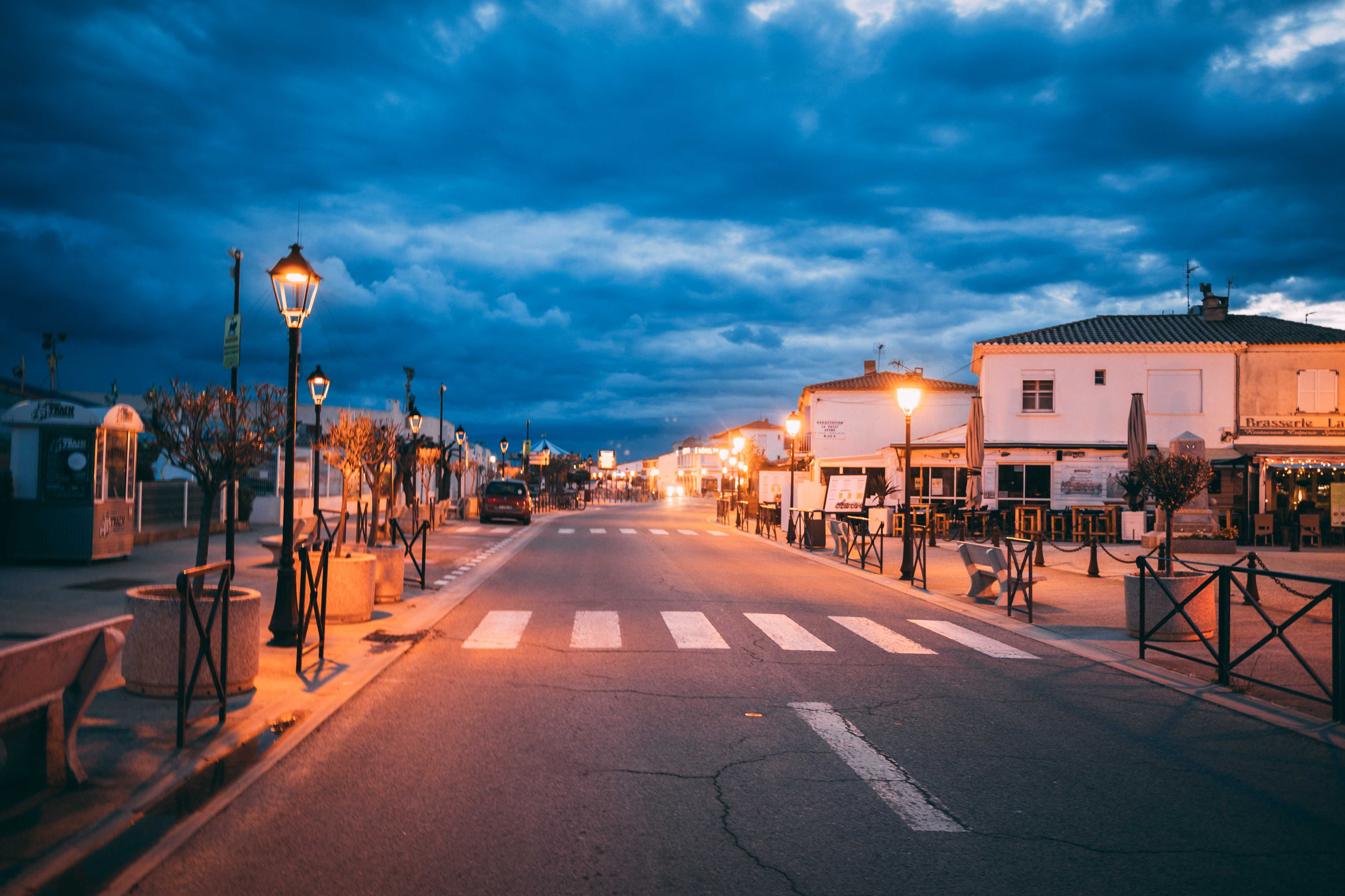 diminishing perspective, cloud - sky, saintes-maries-de-la-mer, street light, street, sign, blue hour, dusk, lights, road, architecture, building, built structure, HD Wallpaper