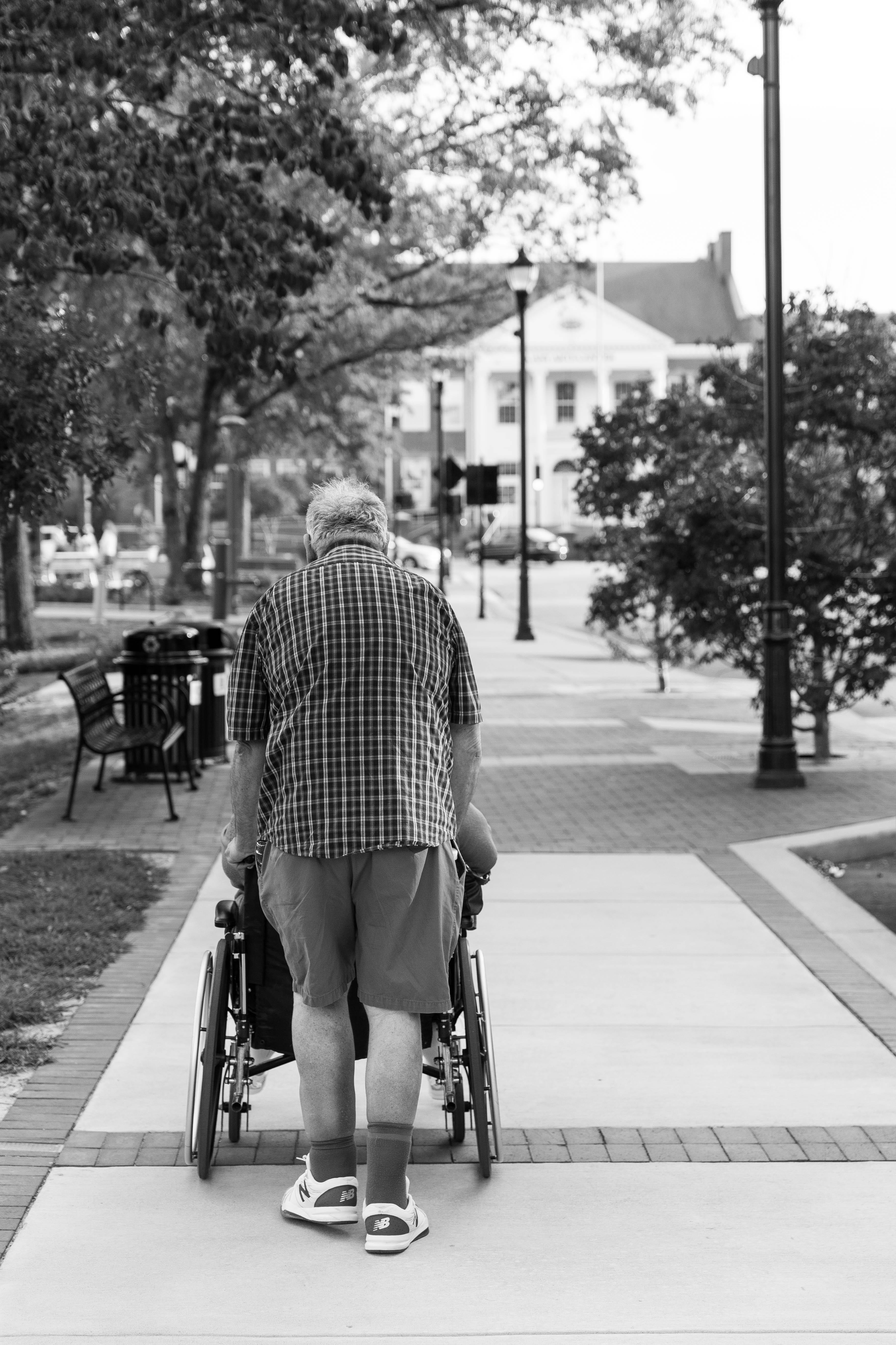 tree, photo, focus on foreground, walking, monochrome, full length, caring, man, street, wheelchair, pushing, elderly, grayscale, one person, architecture, Phone HD Wallpaper