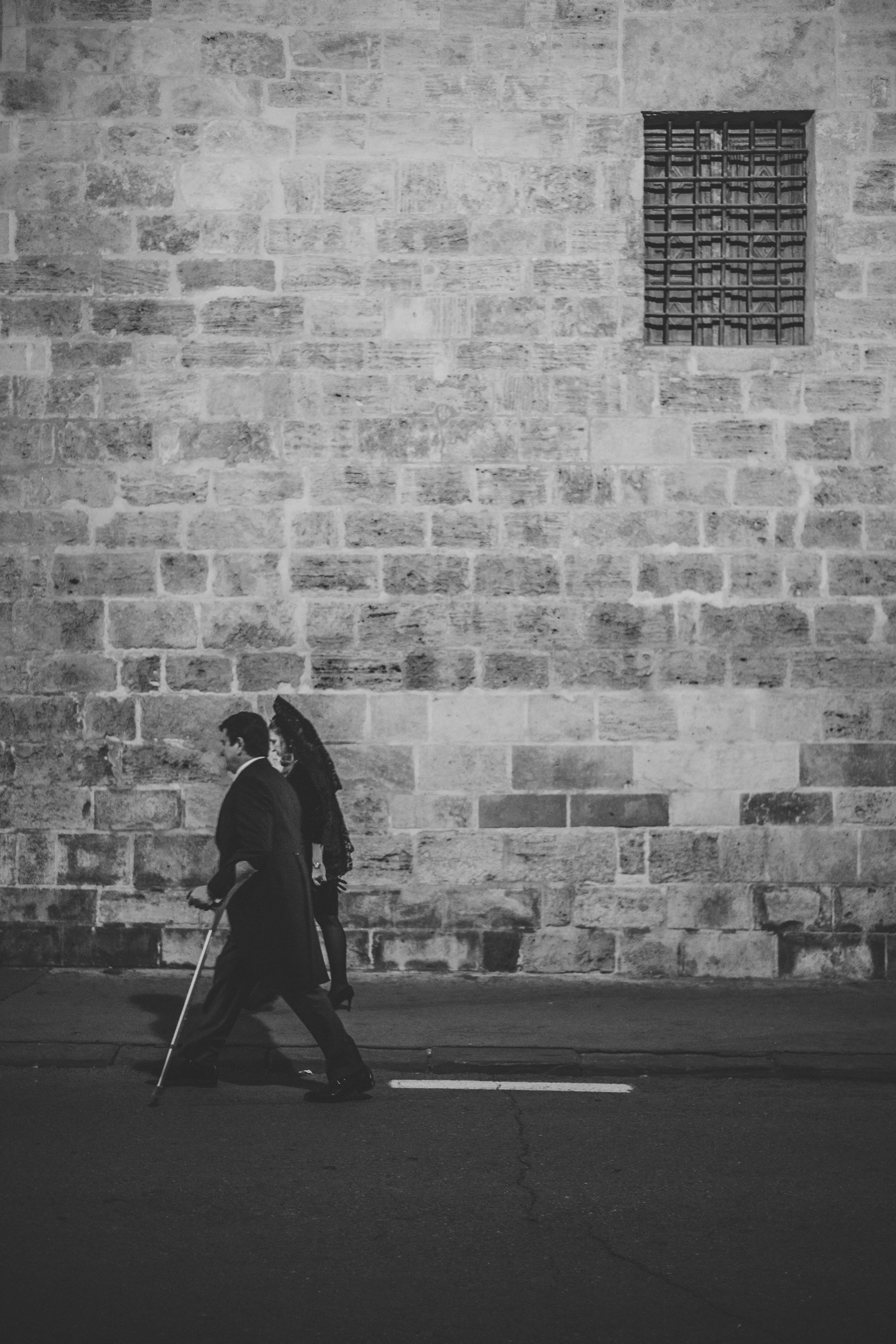 stone wall, men, building, day, stick, apparel, near, architecture, rug, pavement, human, city, built structure, path, walkway, clothing, brick, footpath, Phone HD Wallpaper