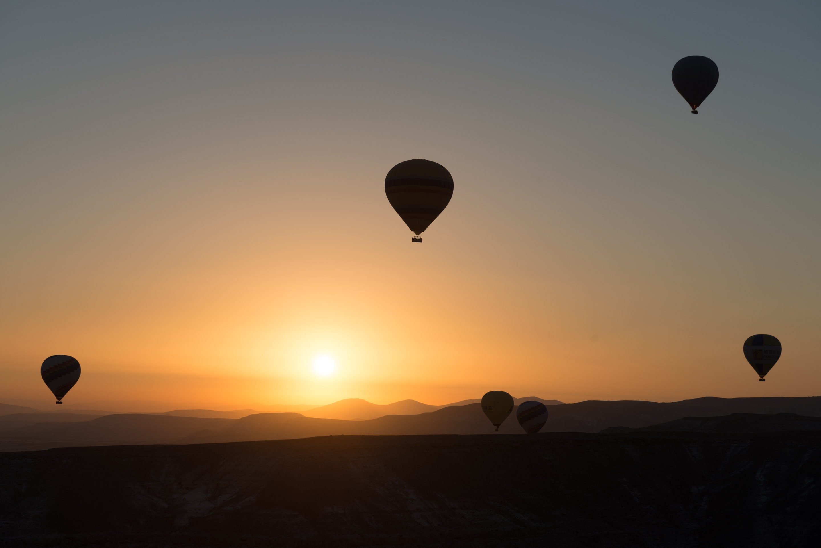 flying, mode of transportation, hot-air ballooning, air vehicle, 2K, mid-air, silhouette, dawn, tranquil scene, landscape, beauty in nature, kapadokia, HD Wallpaper