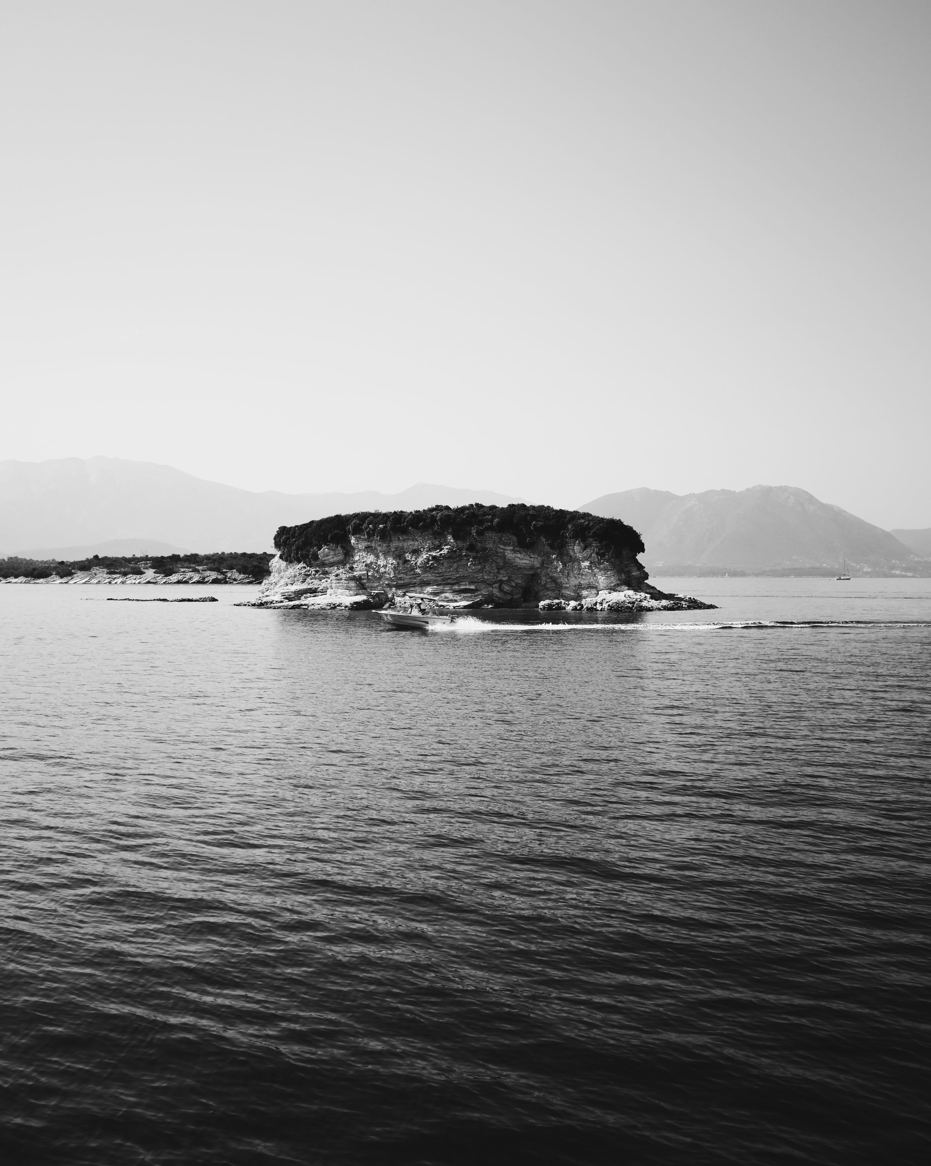 peninsula, ocean, speedboat, near, rocky peak, mountain, sunshine, clear sky, rock, beauty in nature, sun, coast, waterfront, black and white, daytime, Phone HD Wallpaper