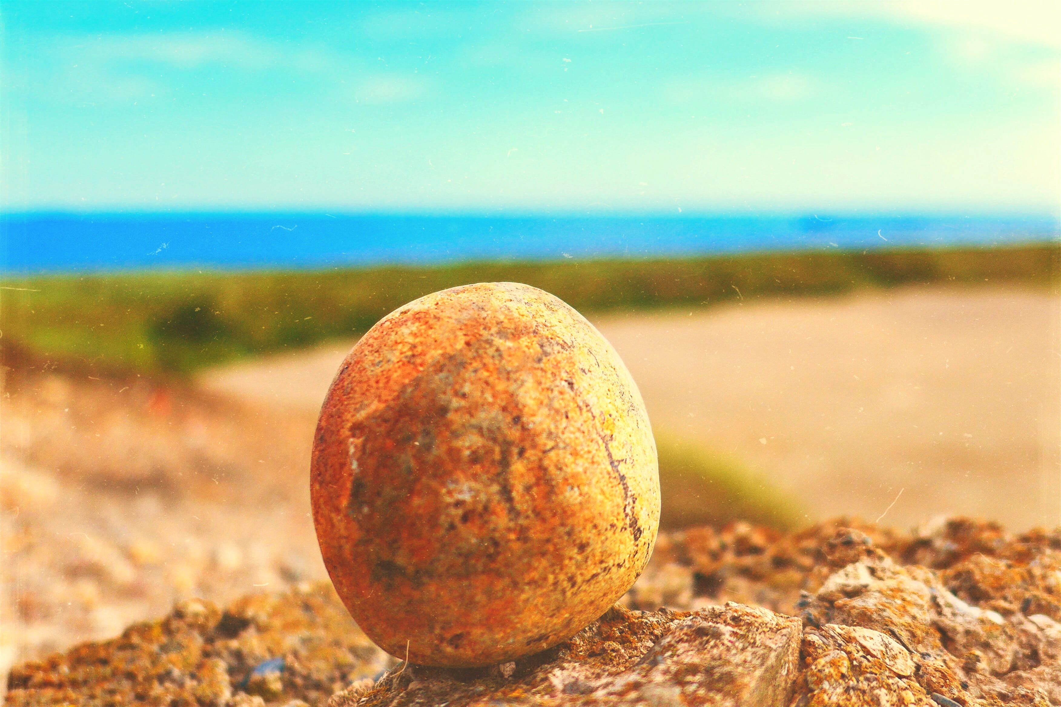 land, outdoors, pebble, close-up, rock, focus on foreground, field, nature, ball of earth, ball of rock, sky, sunlight, water, sphere, selective focus, HD Wallpaper