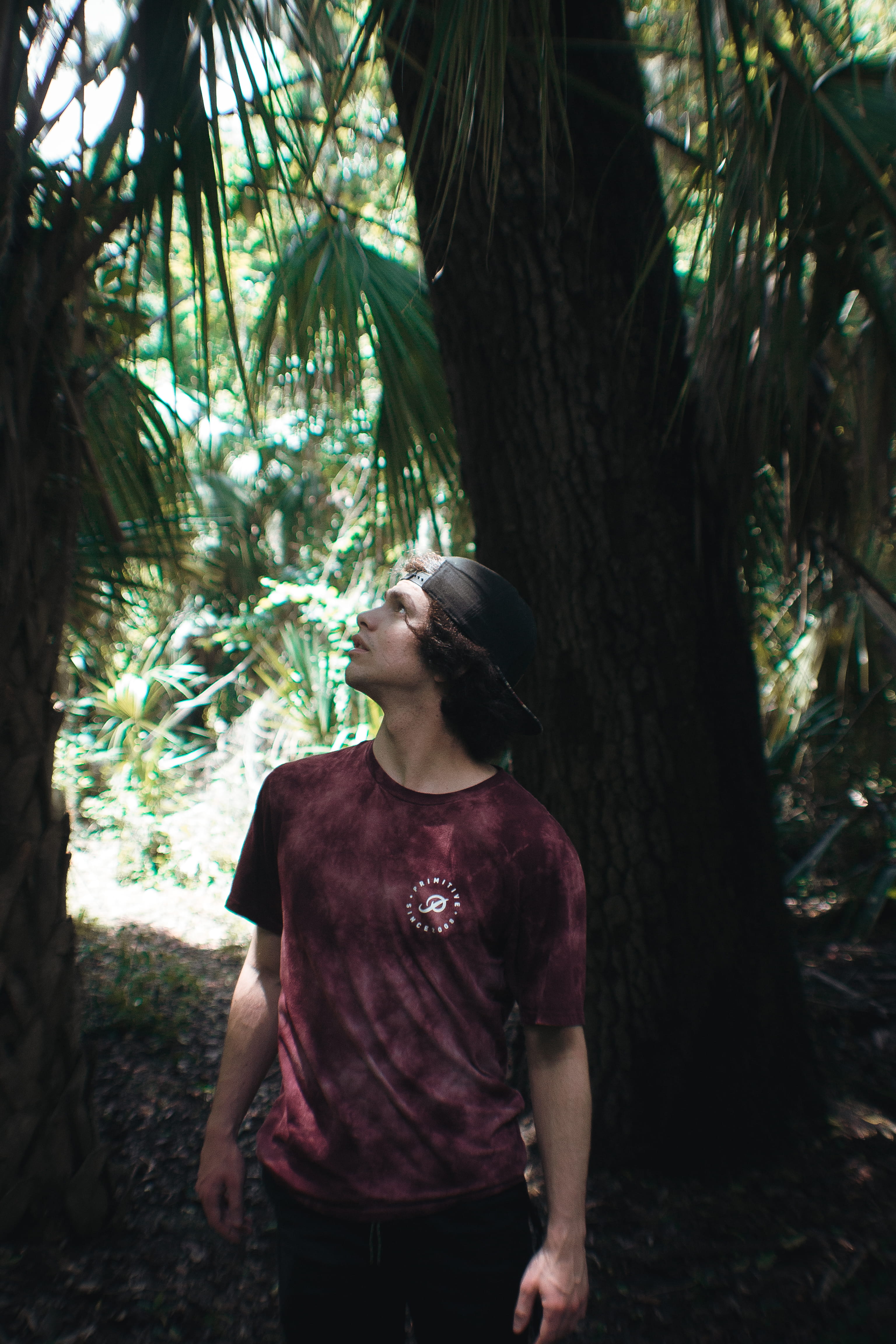 one person, vegetation, t-shirt, person, looking, sleeve, apparel, leisure activity, flare, tree trunk, undershirt, hairstyle, shorts, jungle, 4K, three quarter length, Phone HD Wallpaper