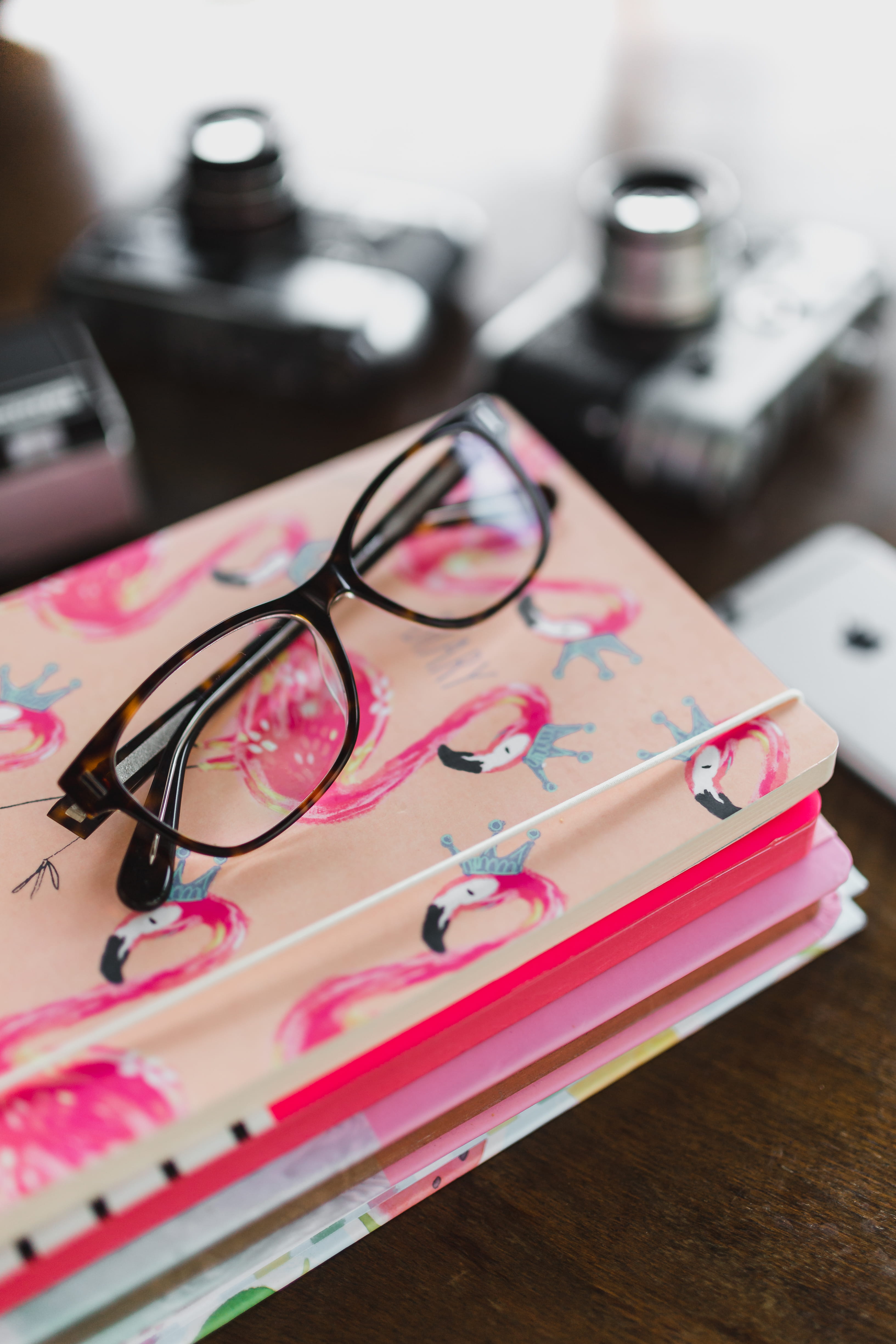 desk, table, selective focus, still life, notebook, eyeglasses, technology, high angle view, pink color, focus on foreground, 4K, personal accessory, no people, Phone HD Wallpaper