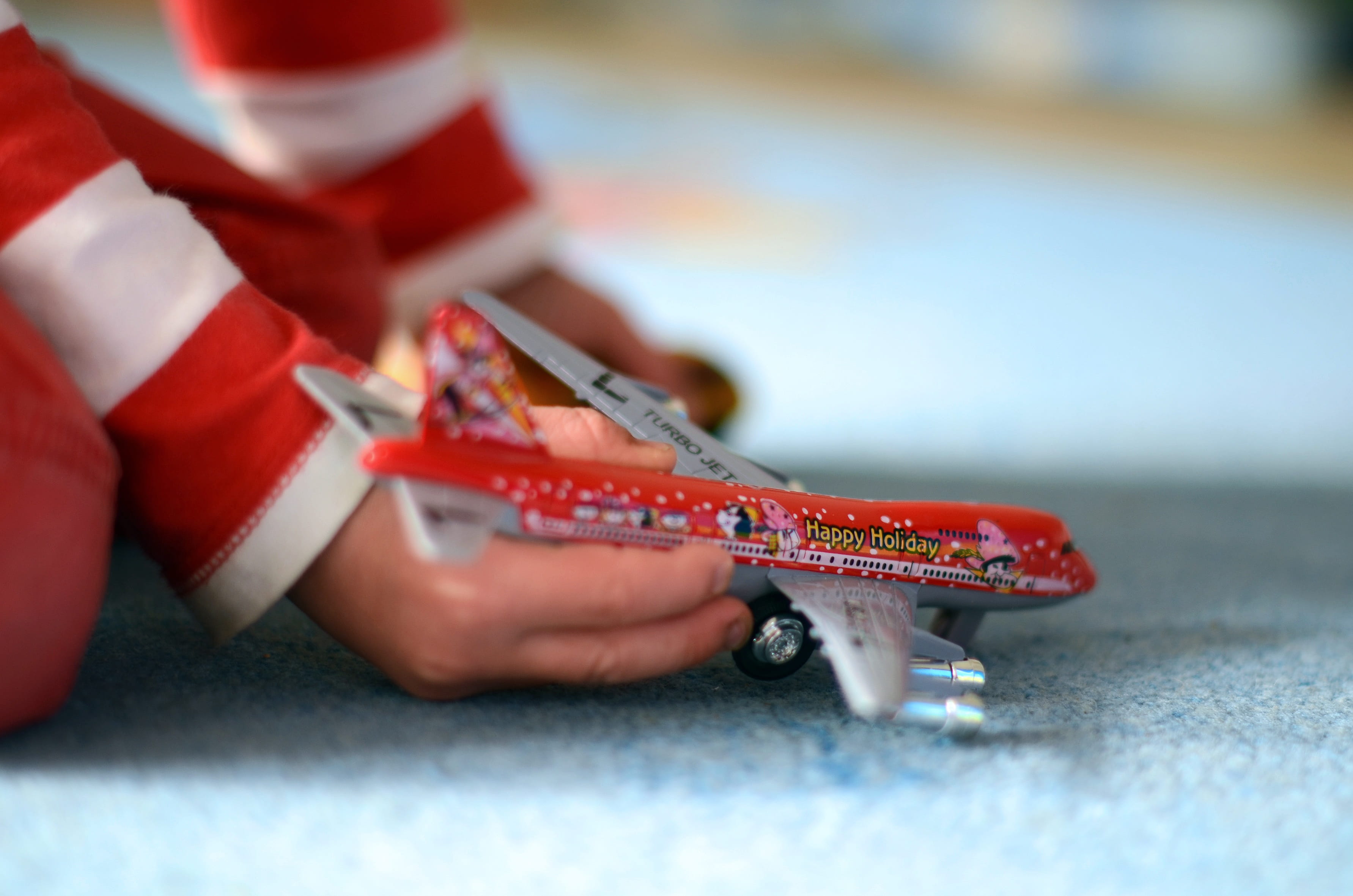 human hand, close-up, childhood, fun, travel, one person, offspring, airline travel, hand, real people, child, 2K, red, selective focus, play, toy, climate, HD Wallpaper