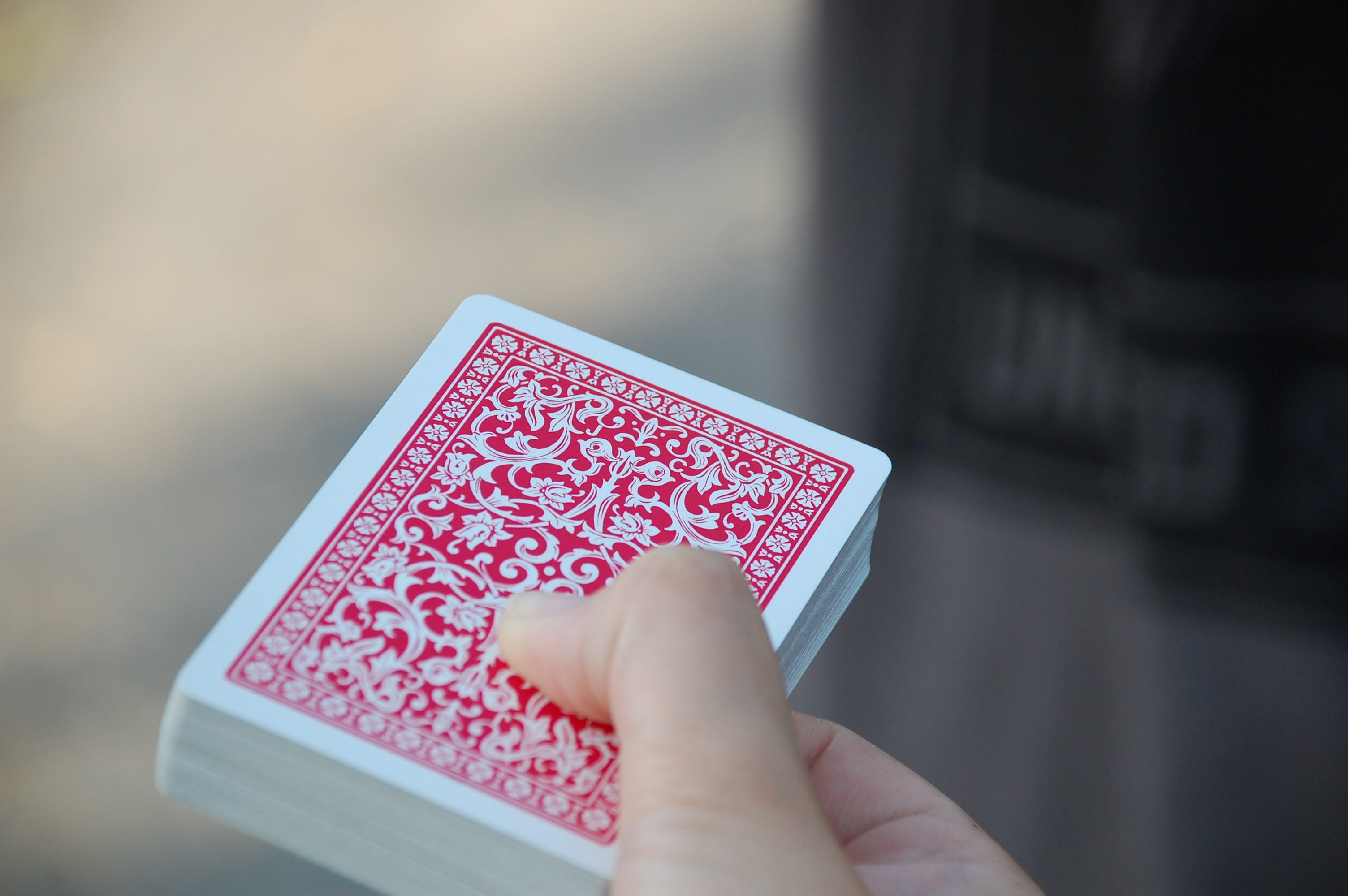 blur, person, communication, red, 2K, text, finger, body part, deck, focus on foreground, hand, holding, outdoors, human hand, playing cards, playing, HD Wallpaper