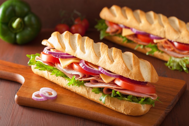 food, baguette, ham, tomatoes, salad, cheese, bell peppers, onion rings, lettuce