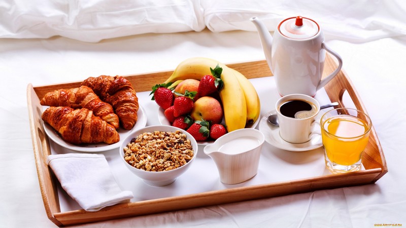 food, fruit, croissants, breakfast, juice, strawberries, bananas, apples, coffee, milk, cereal, napkin, cup, saucer, spoon