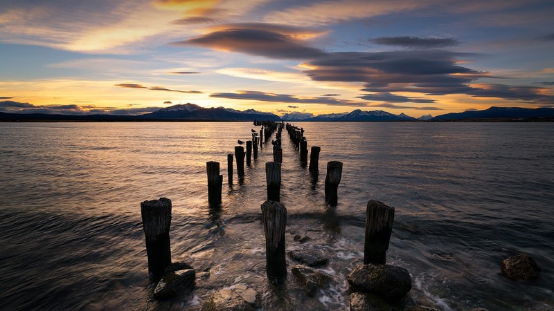 clouds, sky, mountains, snowy peak, snowy mountain, wood, rocks, sunset, water, birds, waves, water ripples, Puerto Natales Pier, pier, Chile, landscape