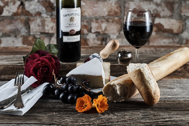 still life, food, wine, bread, grapes, cheese, rose, flowers, knife, fork, napkin, wooden surface