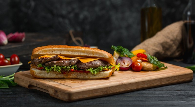 food, bread, meat, vegetables, steak, sandwich, cutting board, cheese, tomatoes, lettuce