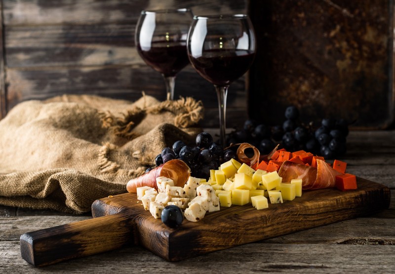 still life, food, grapes, wine, cheese, cutting board, wooden surface, drinking glass