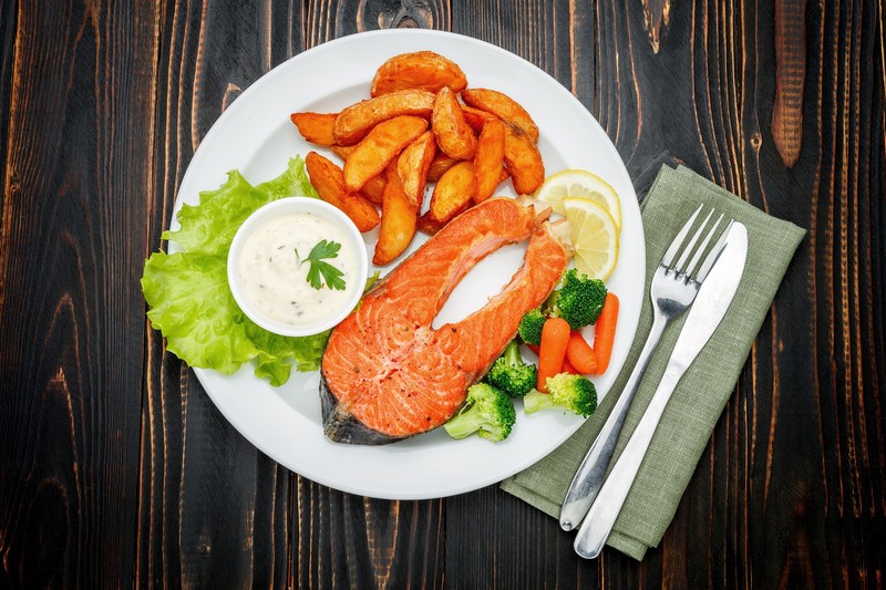 food, fish, fork, lemons, salmon, potatoes, Broccoli, carrots, parsley, plates, table knife, wooden surface, knife and fork