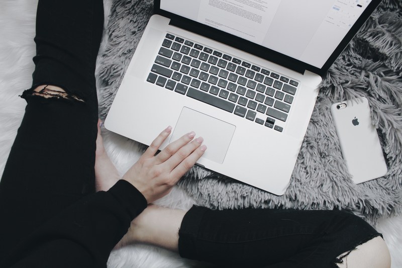 a person in ripped jeans working on a macbook on the floor, ripped jeans and macbook 4k