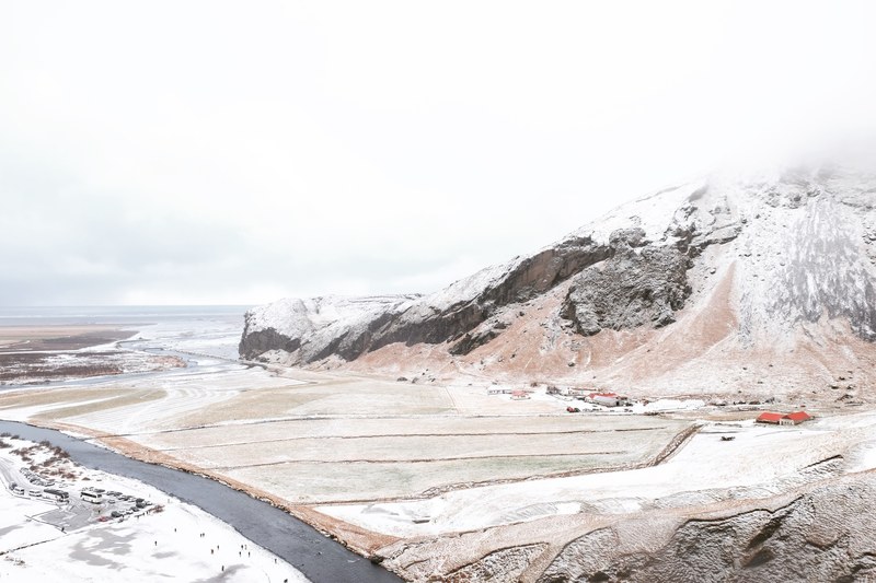 view on a river flowing through snowy plains at the foot of a mountain near skgafoss, icelandic mountains 4k