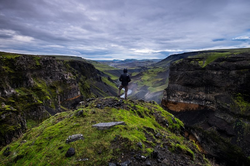 a hiker standing on top of a rock formation overlooking a green river valley, a view of a river valley 4k
