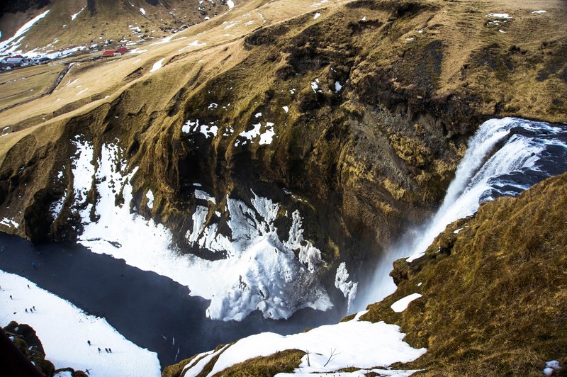 waterfall in iceland flowing into a river between snowy hills, iceland waterfall and river 4k