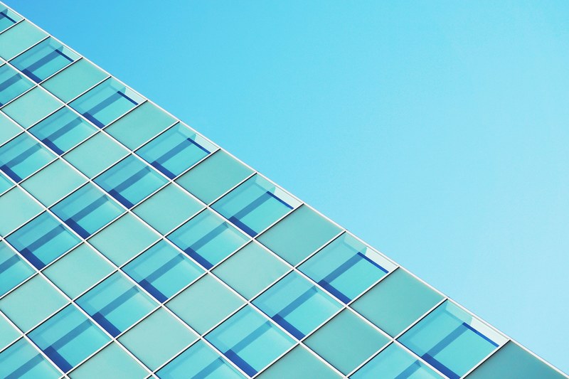 the edge of a glass covered facade against a blue sky, glass covered facade 4k