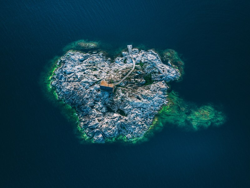 a drone shot of a small building in the middle of a rocky island, archipelago island 4k