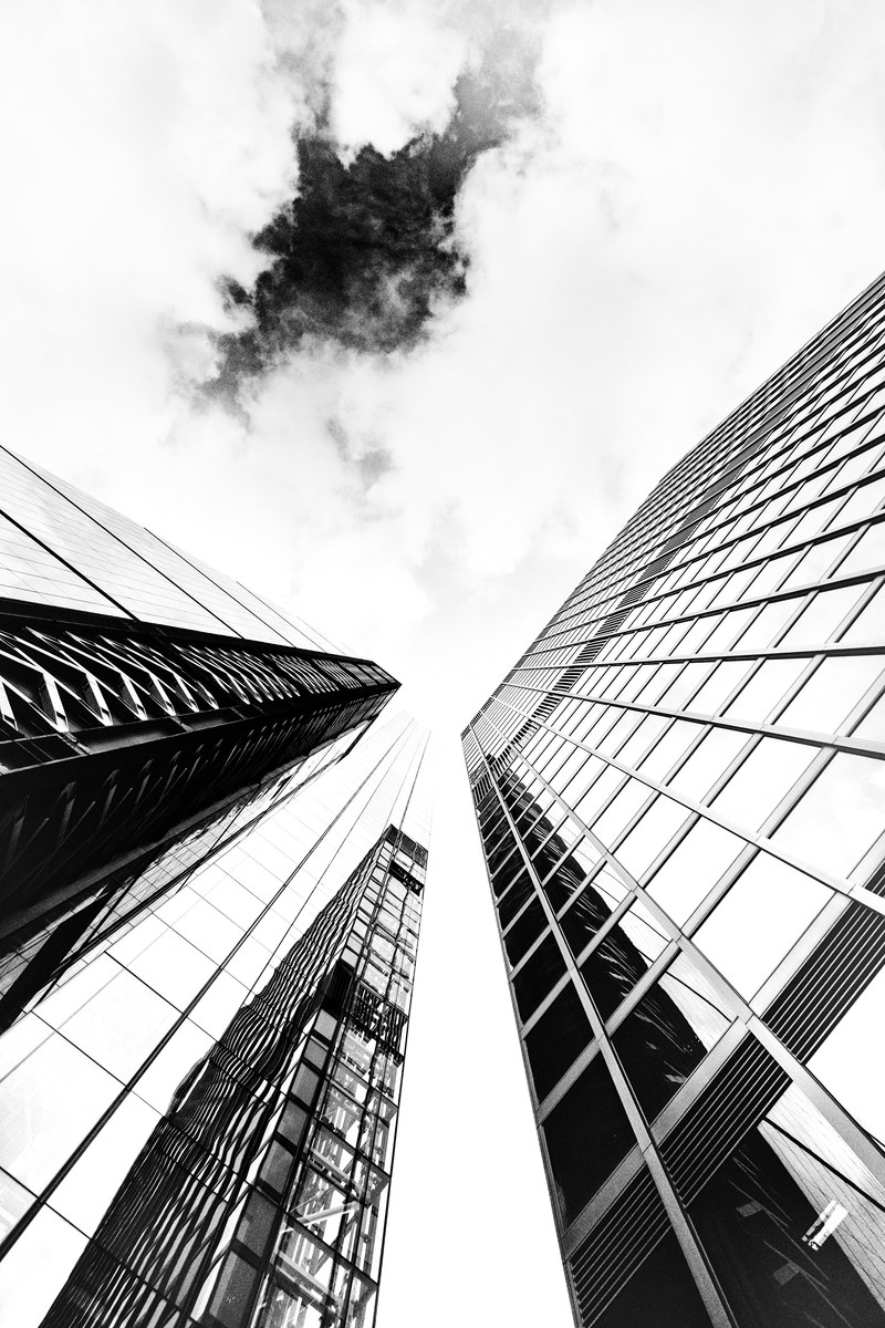 a low angle monochrome shot of glass skyscraper facades under cloudy sky, glass london skyscrapers 4k