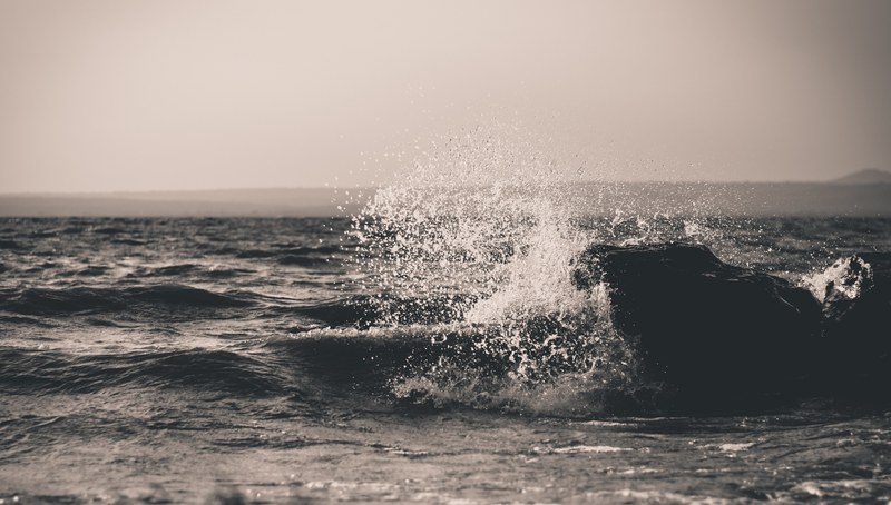 a black and white shot of water splashing over dark waves, water splashing above dark waves 4k