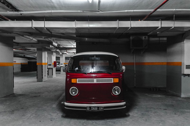 the front of a vintage red minibus parked in an underground garage, red minibus parked underground 4k